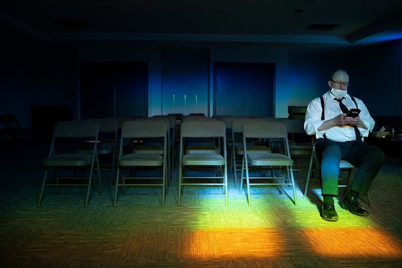 04/10/20 - Funeral Director RIchard Paul sits in an empty chapel at the Funeral Home checking his email.