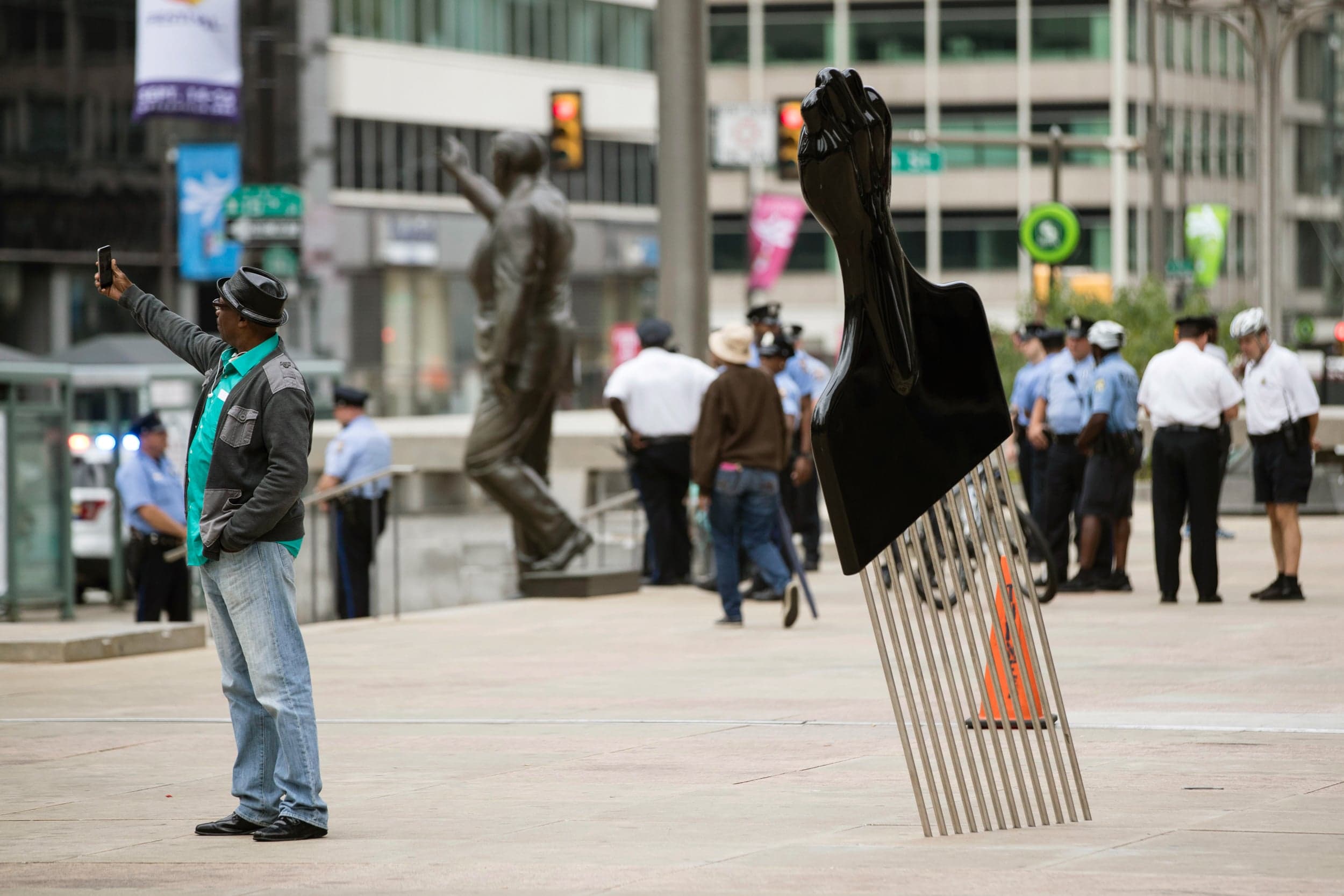 A man takes a selfie in front of Thomas’s sculpture of a 12-foot Afro pick, called All Power to All People, in view of a statue of Philadelphia’s former mayor and police commissioner Rizzo (Matt Rourke/AP/CP)