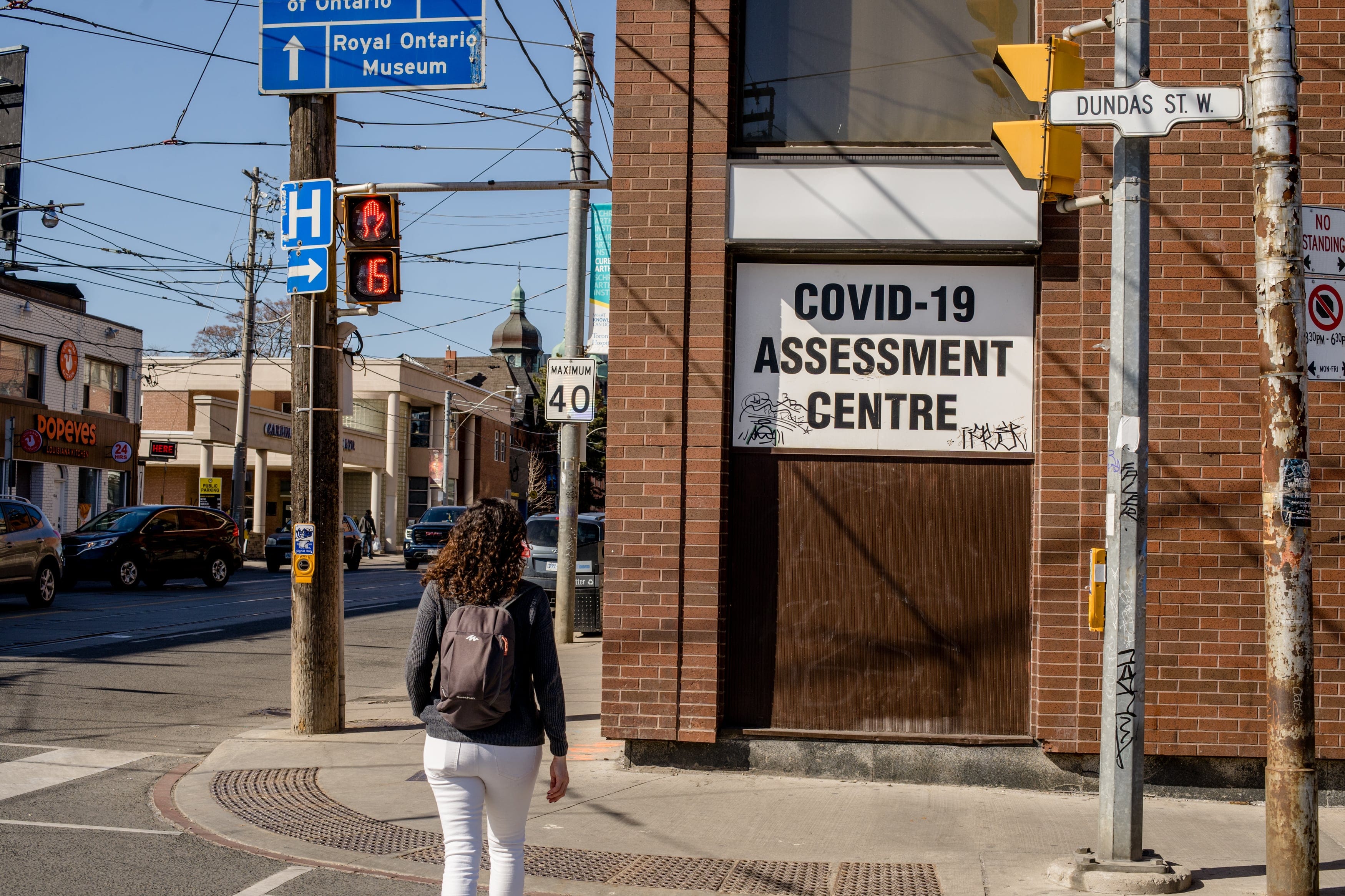 TORONTO, CANADA - 2021/03/21: Woman walks across the street, towards the COVID-19 assessment centre at Toronto Western Hospital. The COVID-19 assessment centre is where city residents go for COVID-19 testing. (Photo by Shawn Goldberg/SOPA Images/LightRocket via Getty Images)