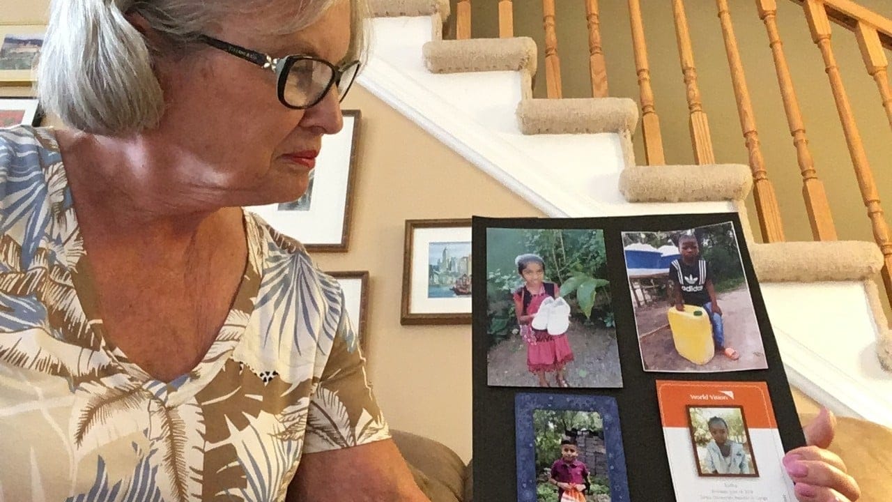 Cheryl Pitchford holding photos of the children she has sponsored