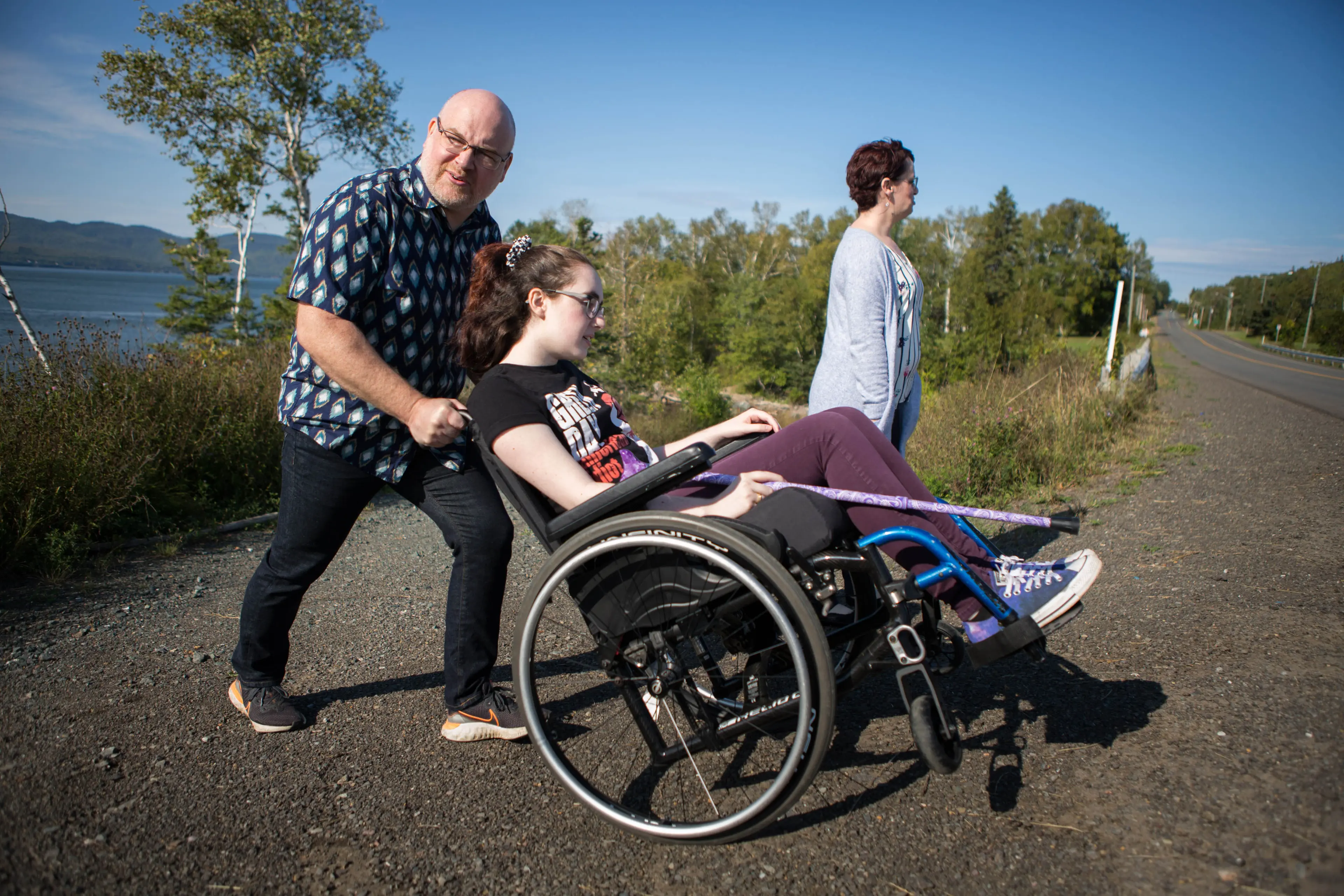 Gabrielle Cormier's father André-Marc Cormier pushes her across the street in front of her family home in Dalhousie Junction, NB, alongside her mother Marie-Line Daigle. Gabrielle is one of the youngest patients diagnosed with a mysterious brain illness with clusters of cases on the north shore of the province and in the Moncton region. (Photograph by Chris Donovan)