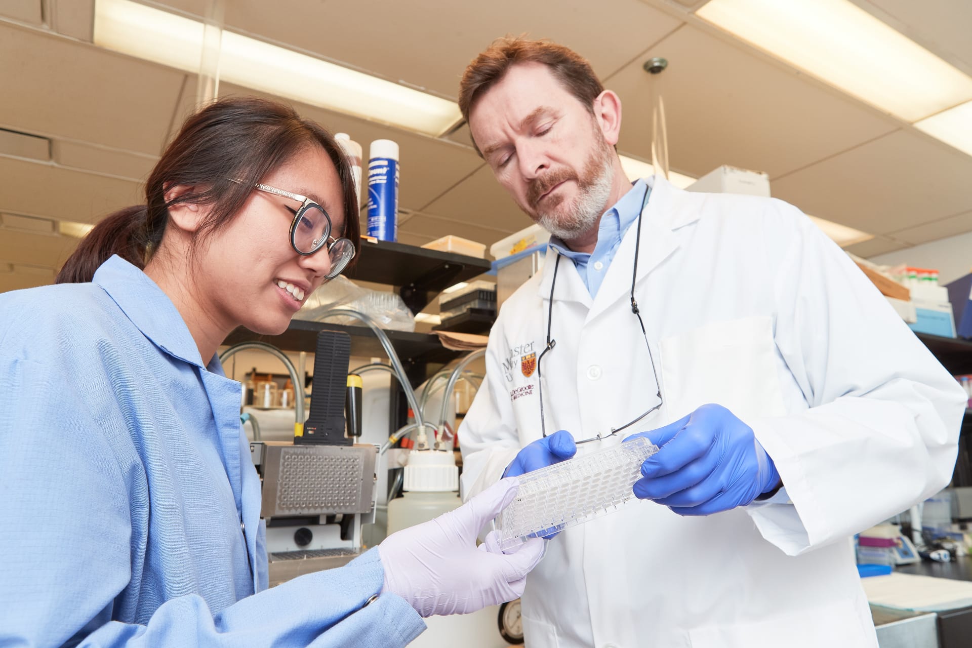 Man and woman in lab coats looking at test tube holders