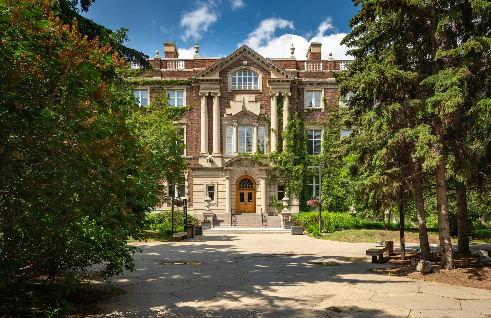 Tall brown university building flanked by trees on either side