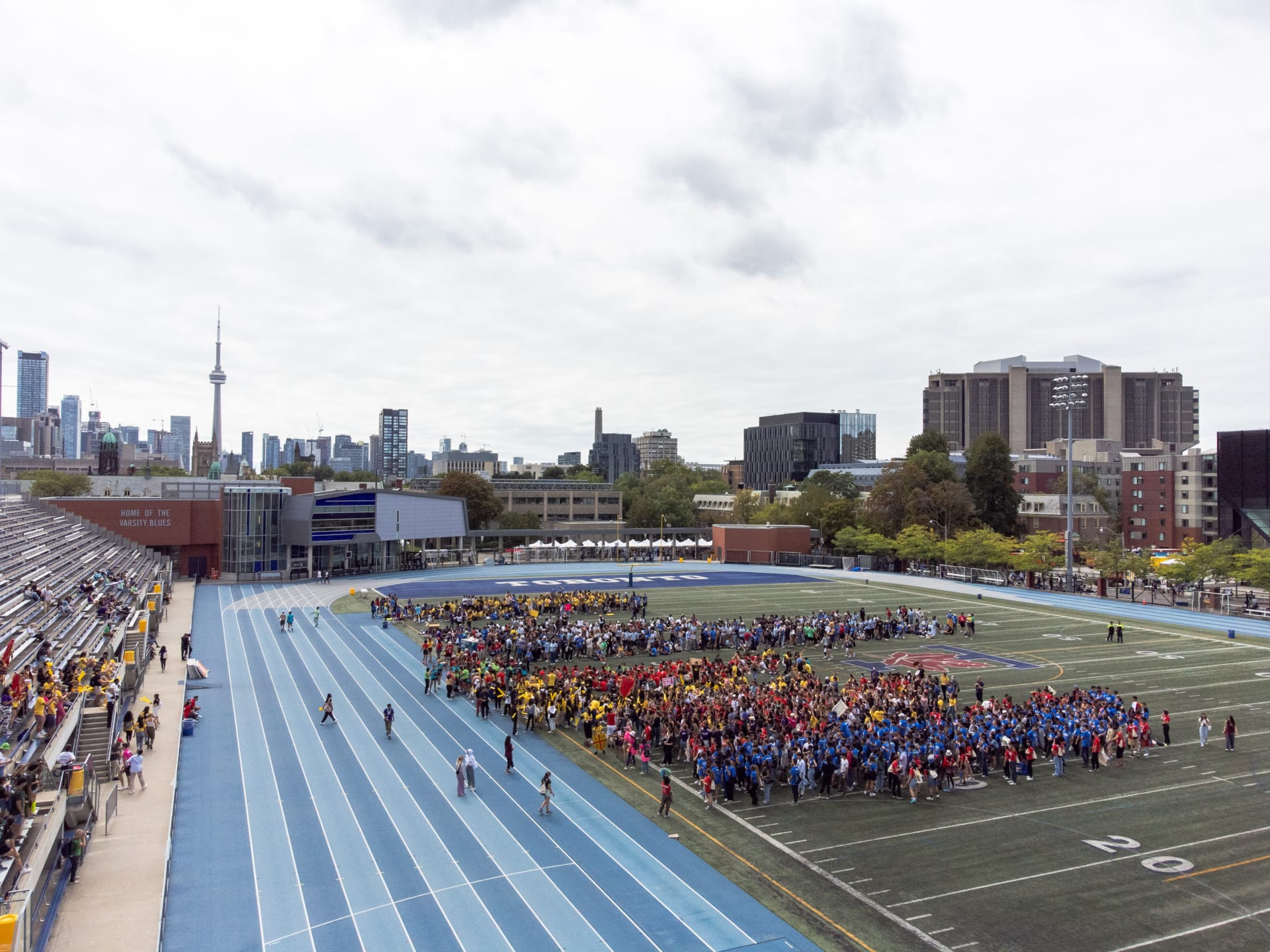 overhead shot of blue race track and people on the field next to the racetrack