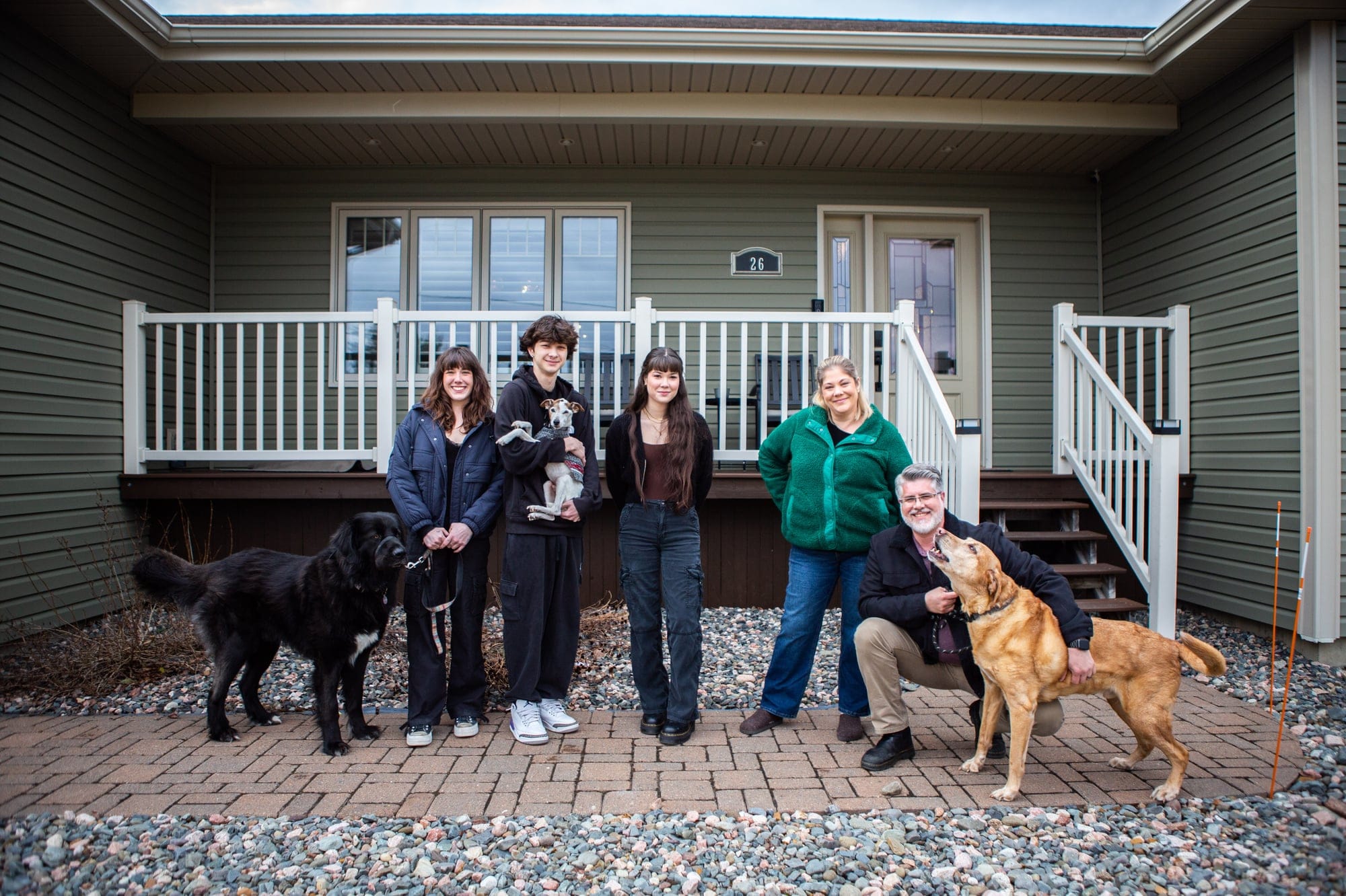 The Ostrander family pose in front of their home with three of the four family dogs in Douglas Parish on the outskirts of Fredericton, NB, on March 19, 2024. From left: Abigail Lynch, Aidan Ostrander, Kaiya Ostrander, Tracy Ostrander, and Scott Ostrander. (Photograph by Chris Donovan)