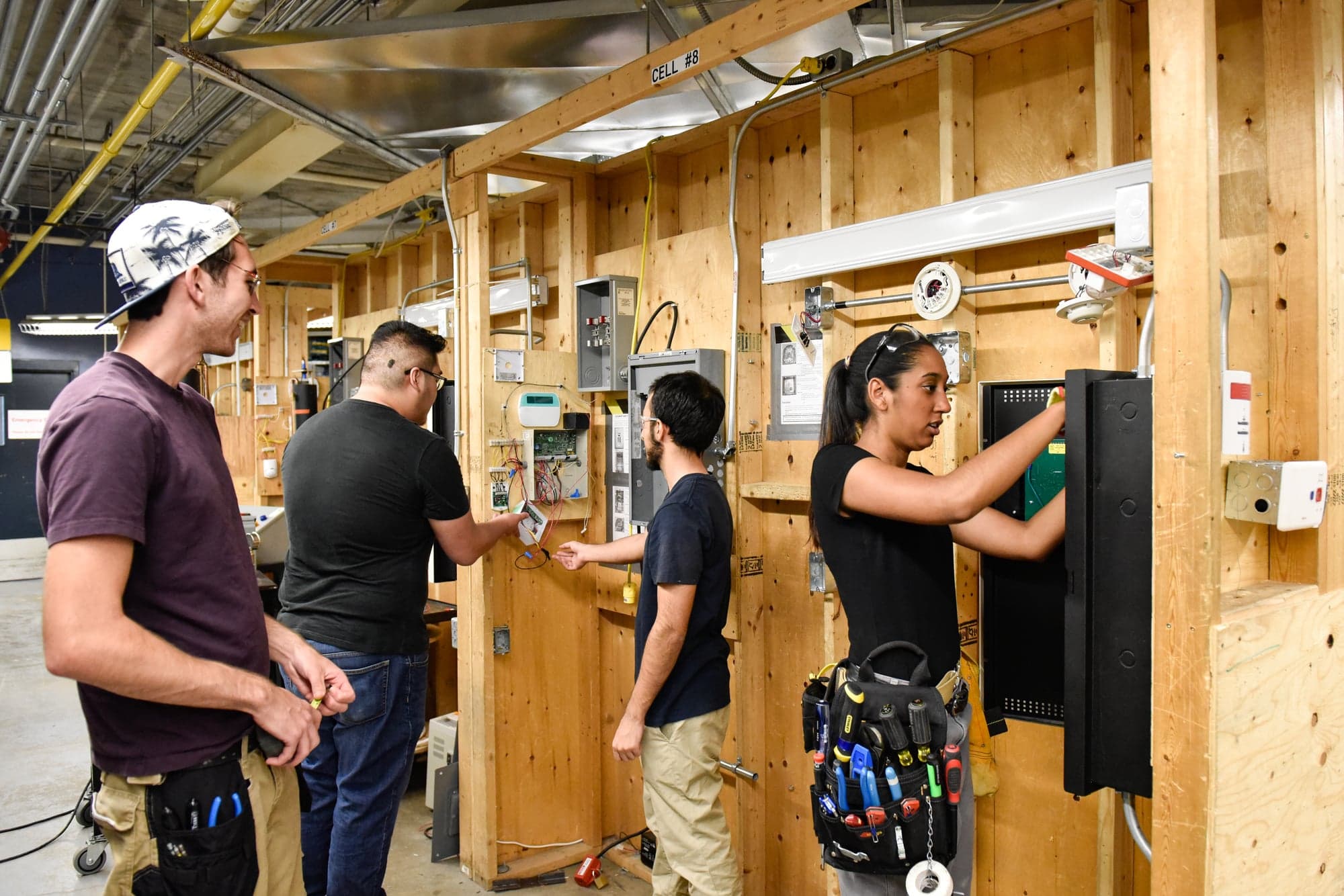 students in a wooden room working on electrical boards