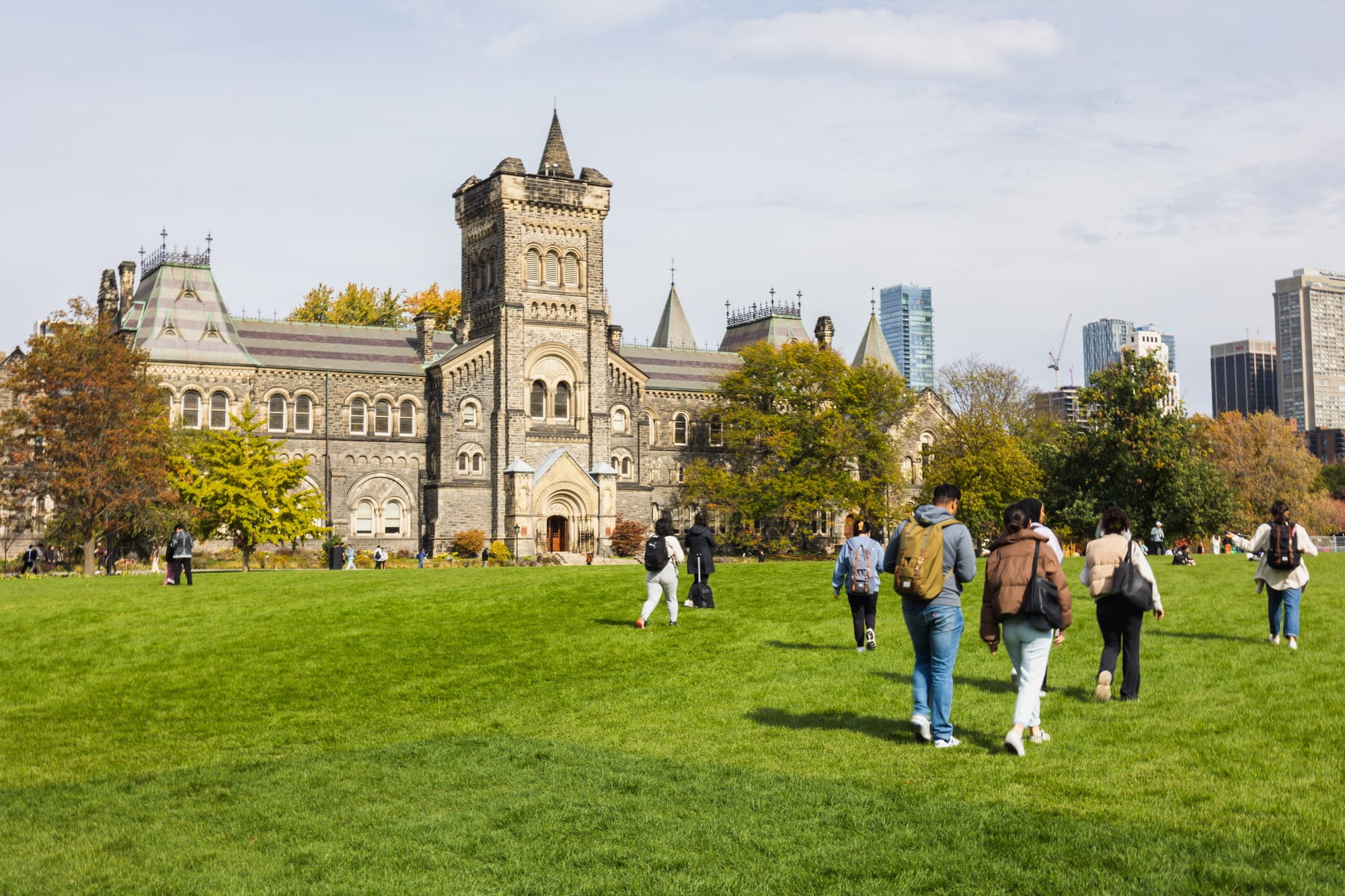 The front campus of the University of Toronto, with students walking on green grass