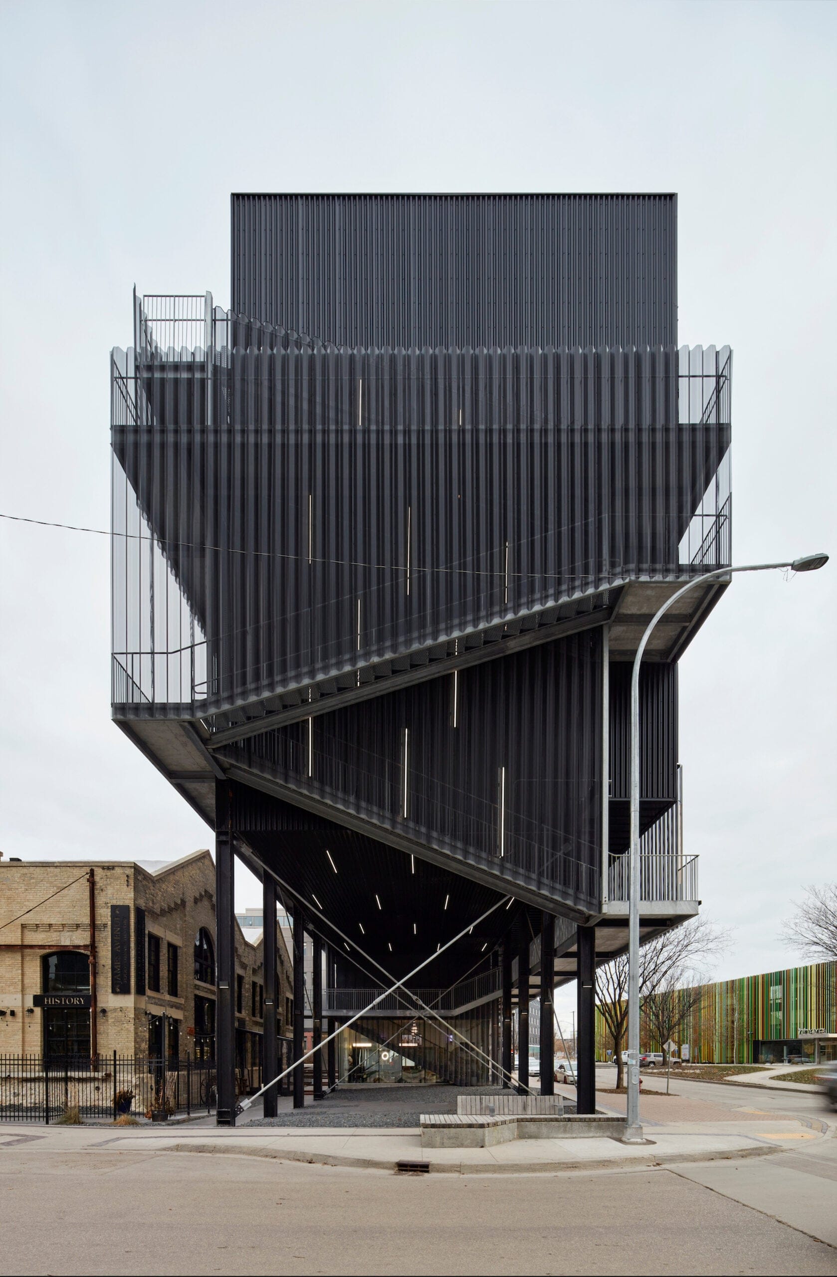 The geometric black metal structure of the Winnipeg Pumphouse, sitting on a concrete street