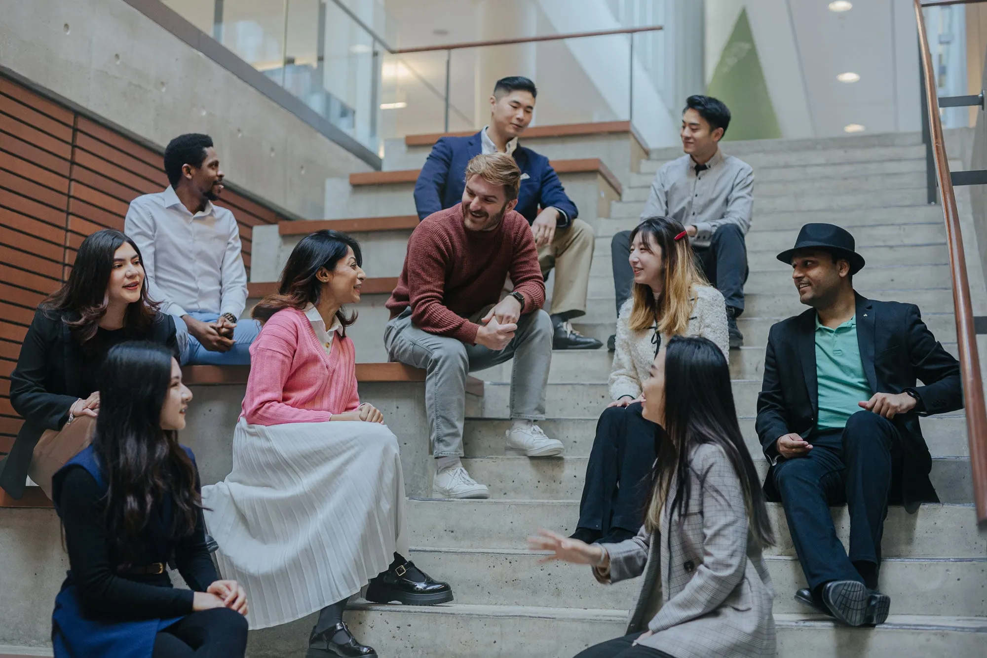 Business students chatting on steps inside of a university building.