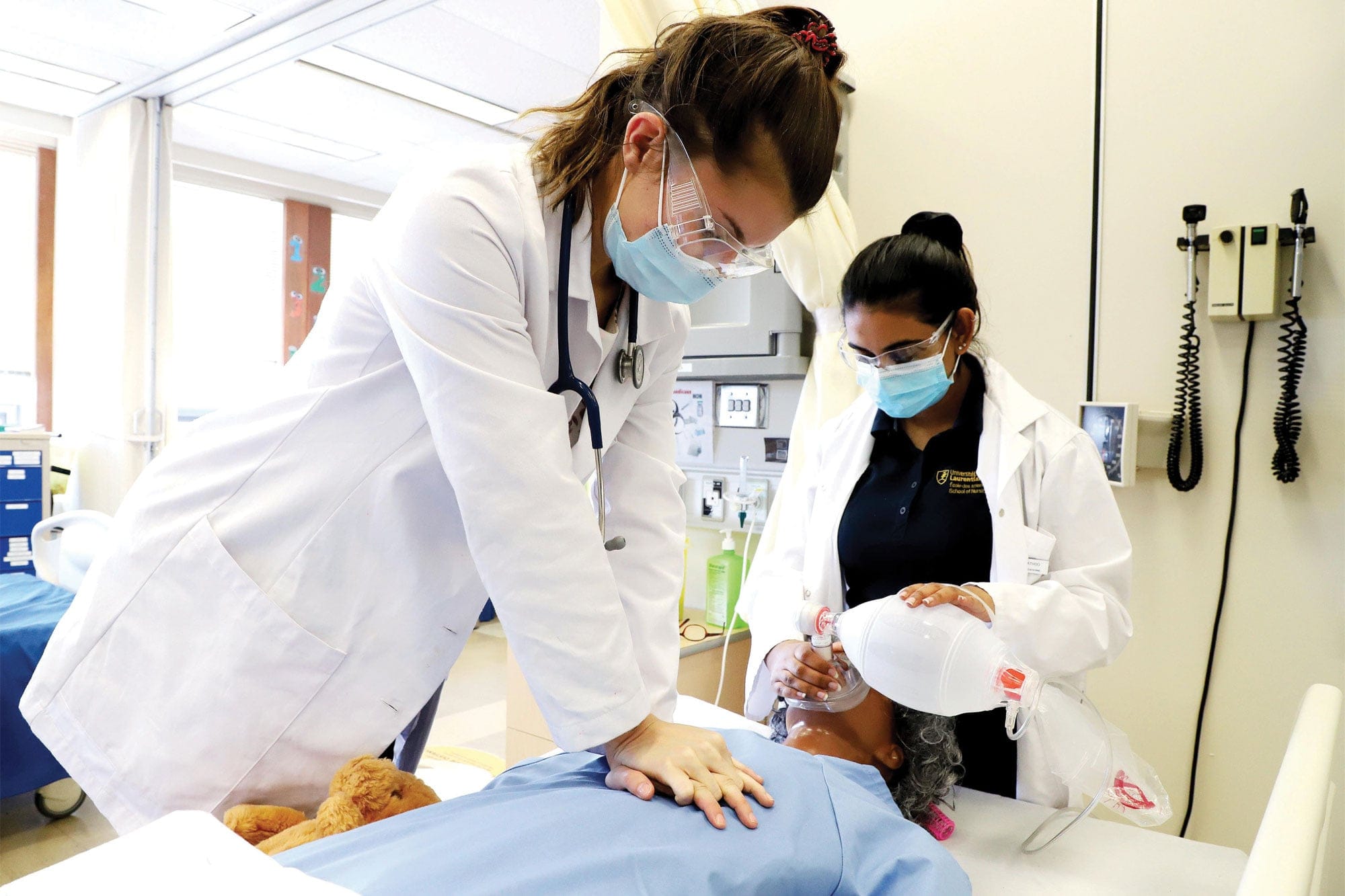 Two nursing students practicing CPR on a dummy.