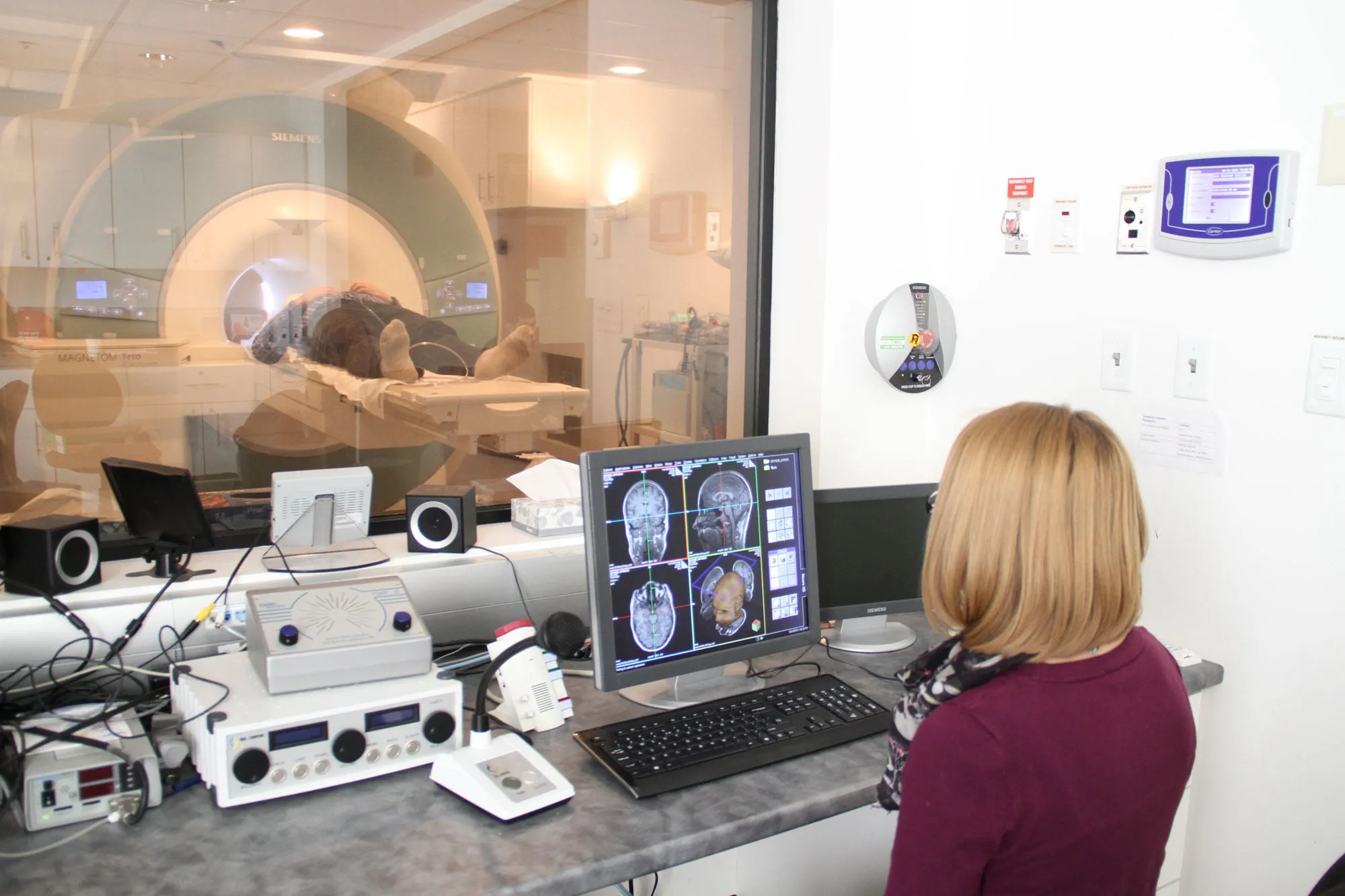 The back of a student looking at a screen of four brain scans on a computer monitor.