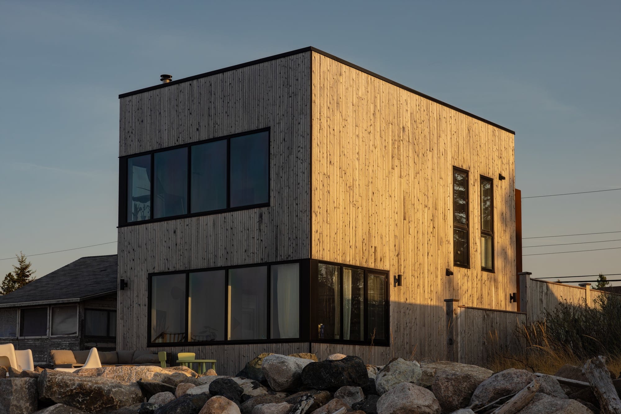 A cedar-clad modern beach house at dusk