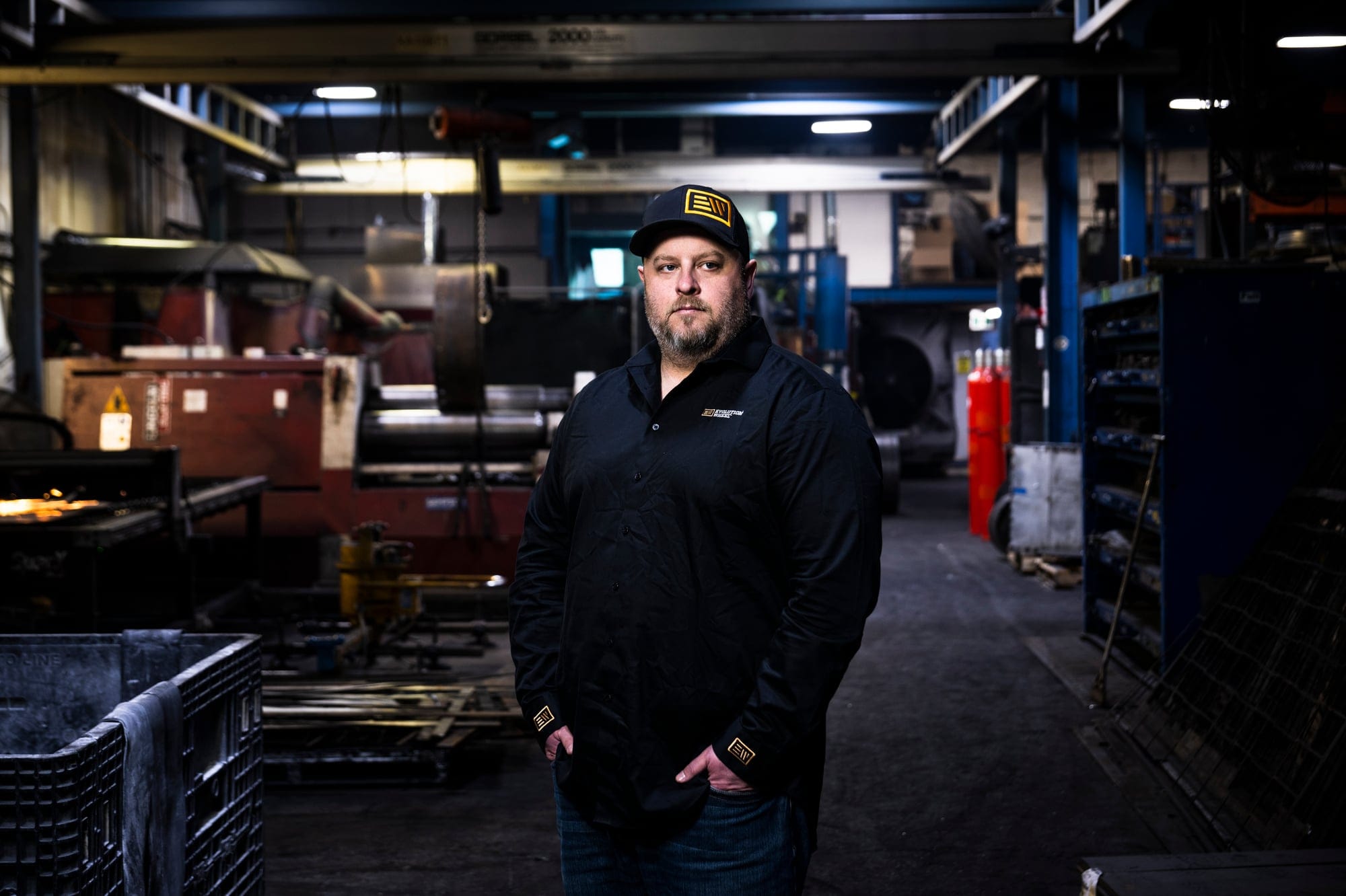 A man in a black work jacket and a black hat