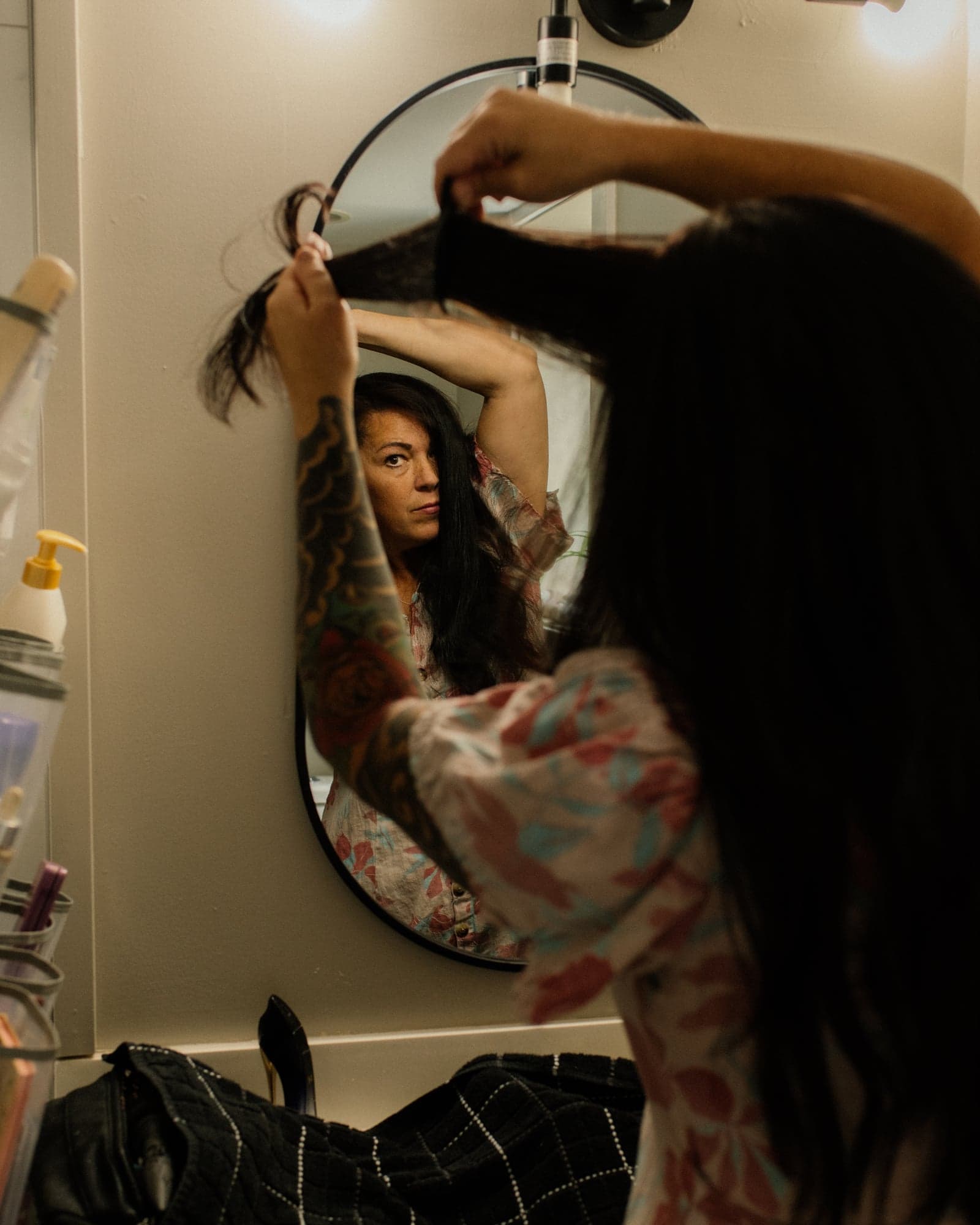Jeni Gunn standing in the bathroom, looking in an oval mirror