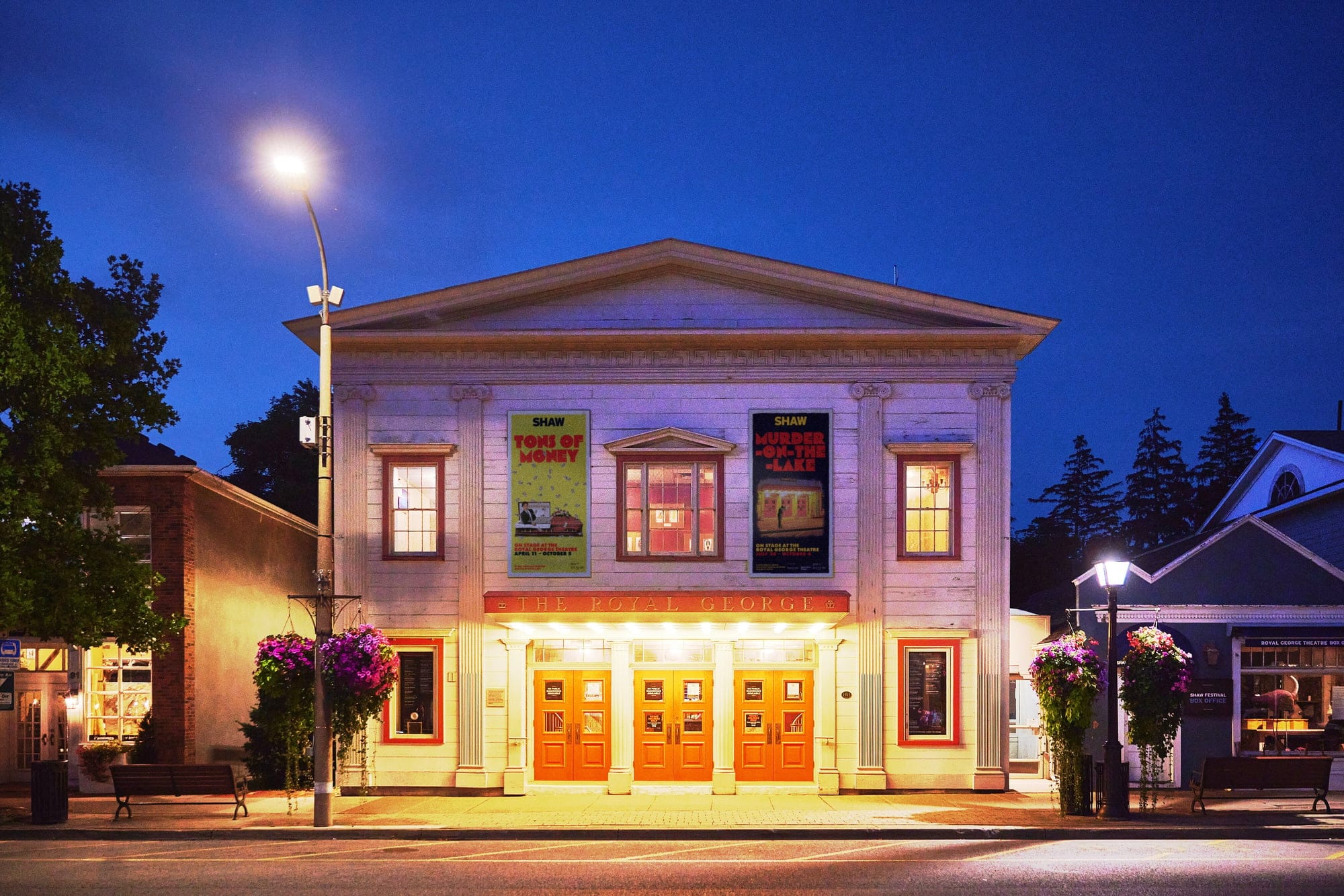 A theatre building in the evening, lit with golden light along the front and inside the windows