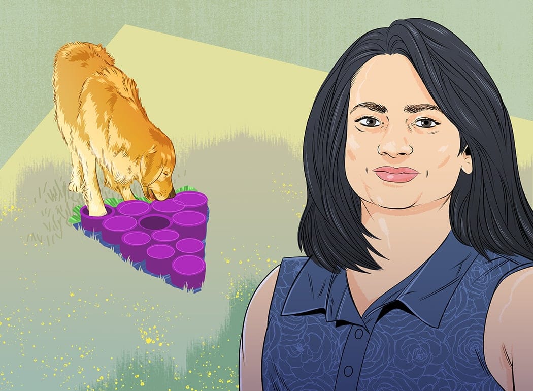 A woman in a blue shirt with a dog behind her, its nose buried in a snuffle mat