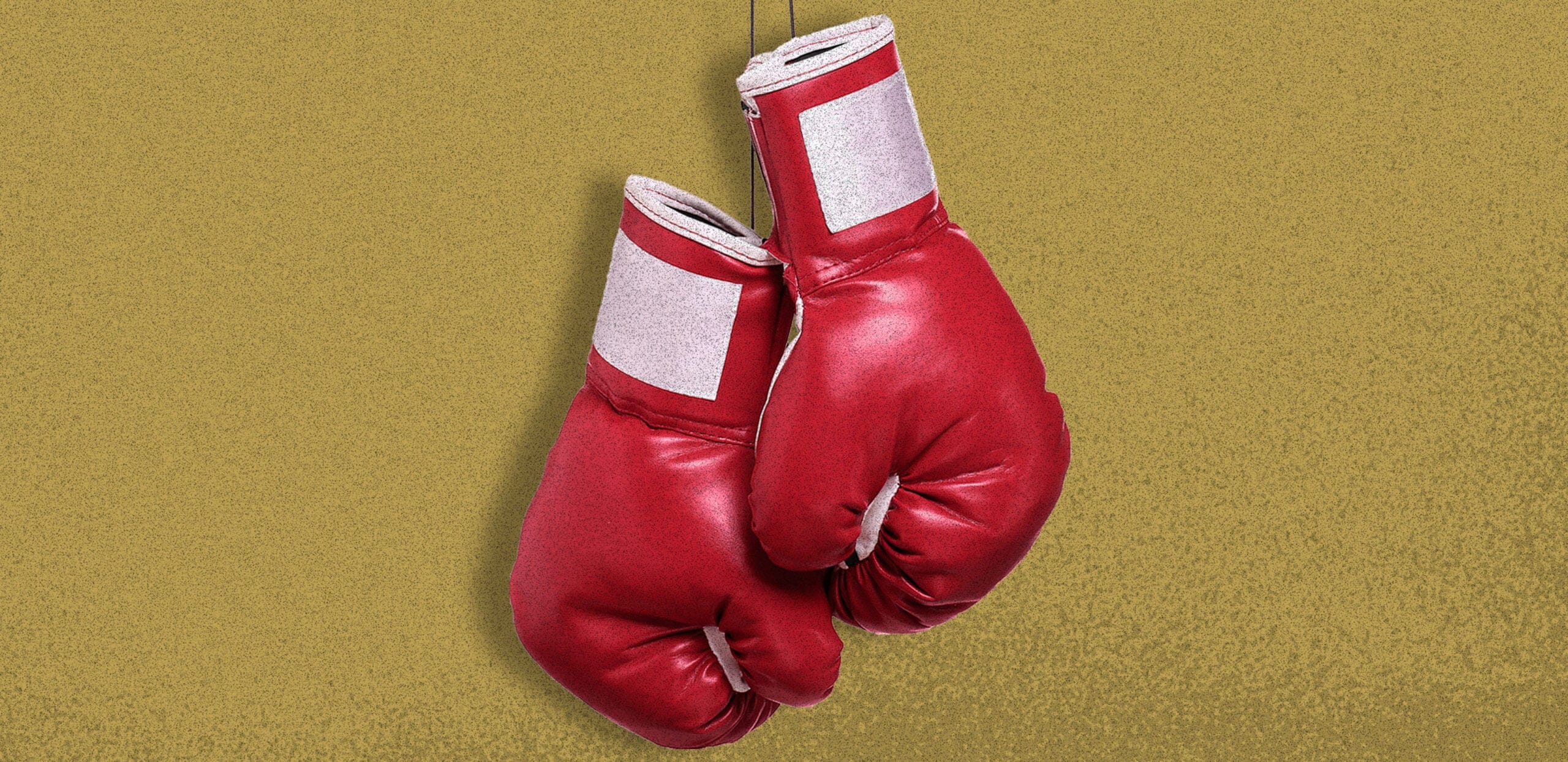 A pair of red boxing gloves against a gold background
