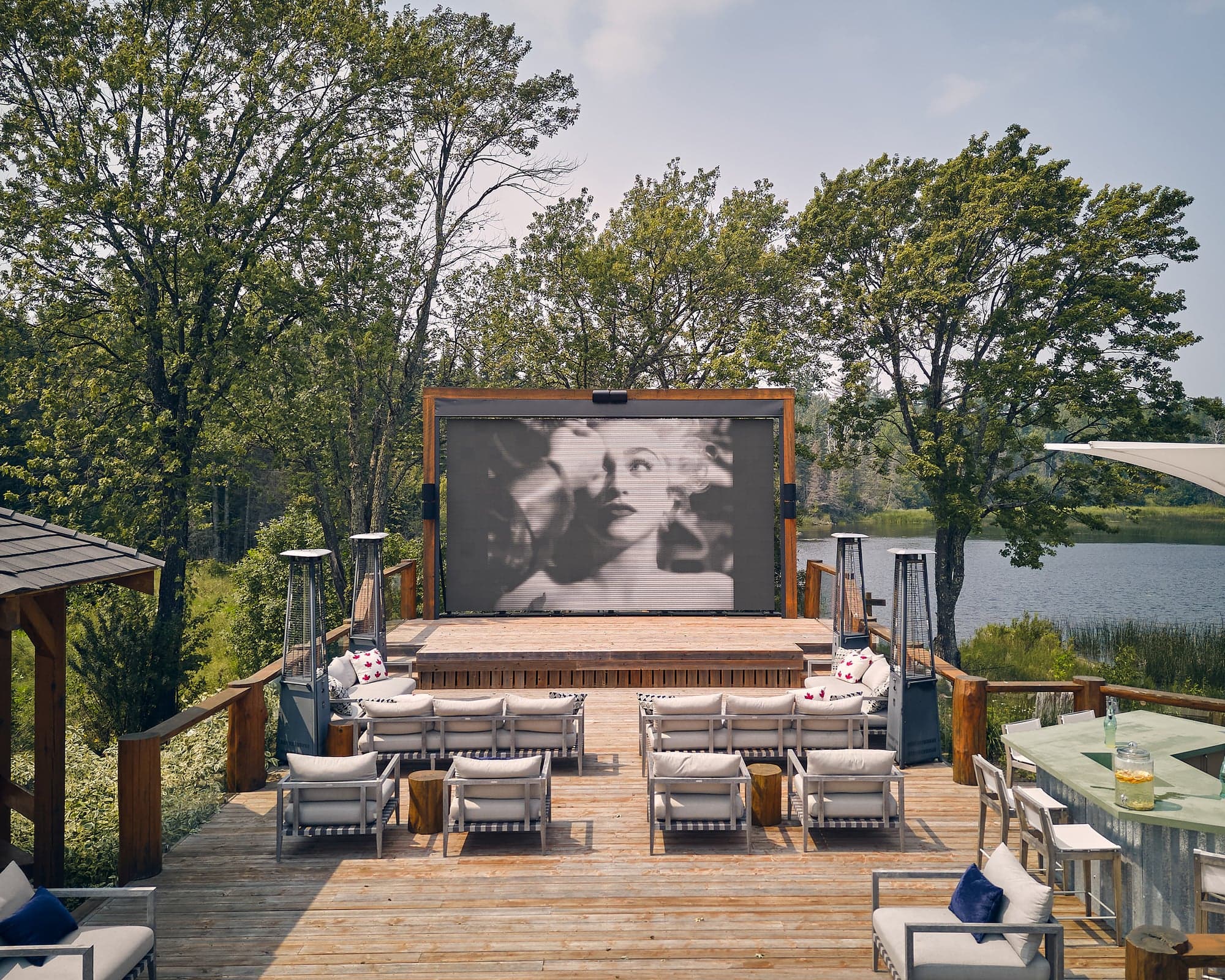 An outdoor movie theatre with white patio chairs and a screen with a blonde woman on it