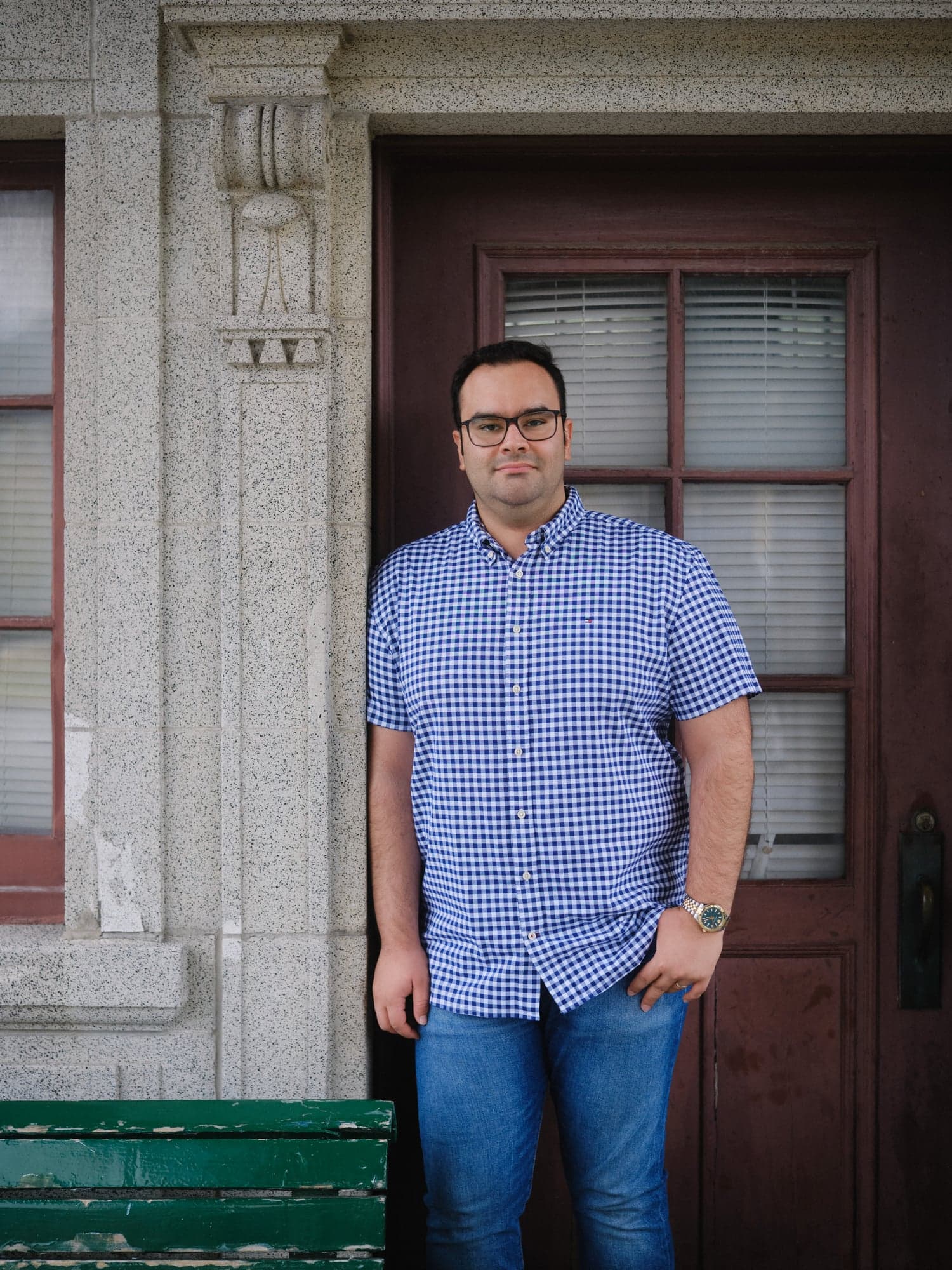 A man in a blue shirt standing in front of a house