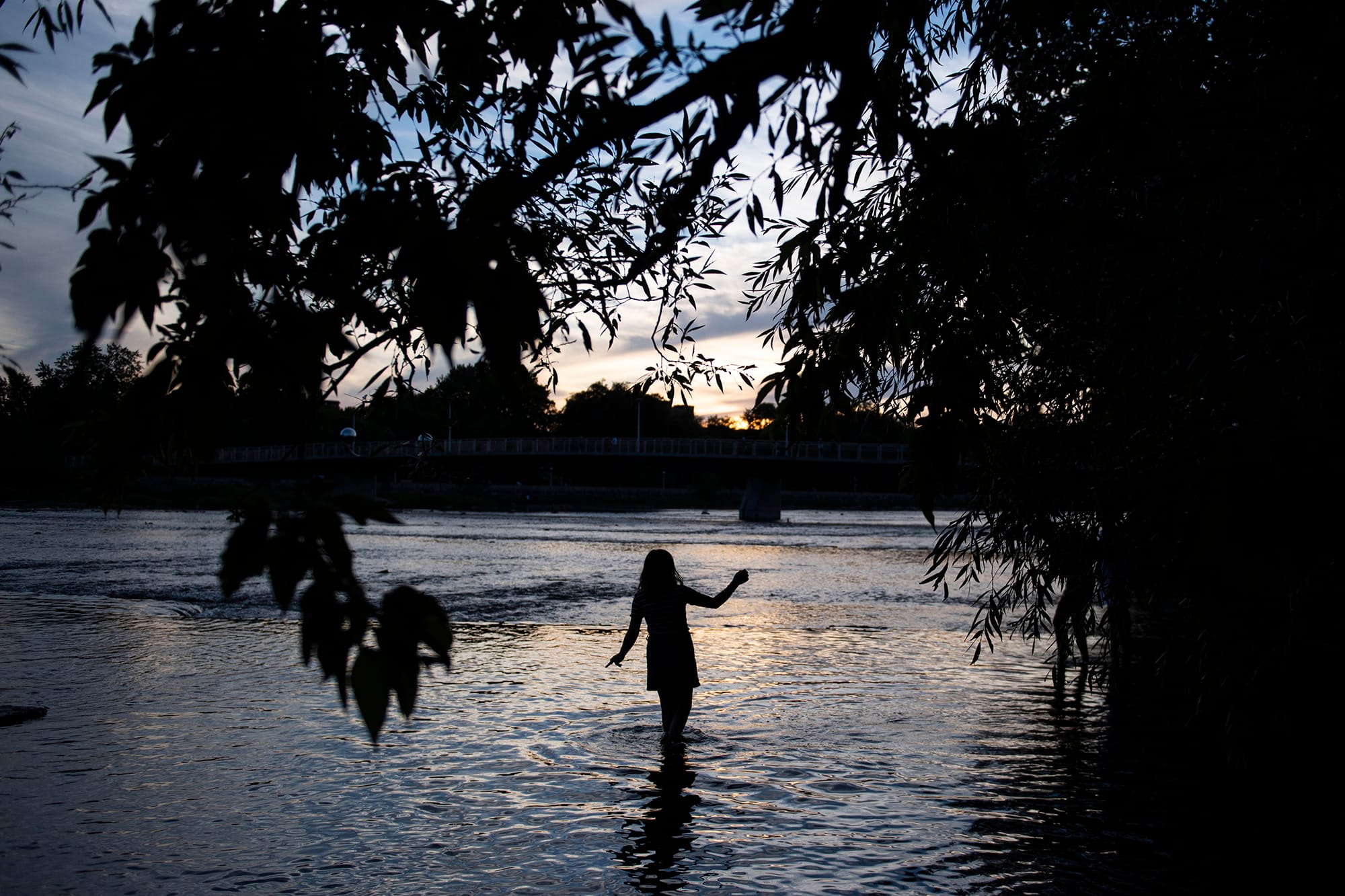The silhouette of a person wading into a river