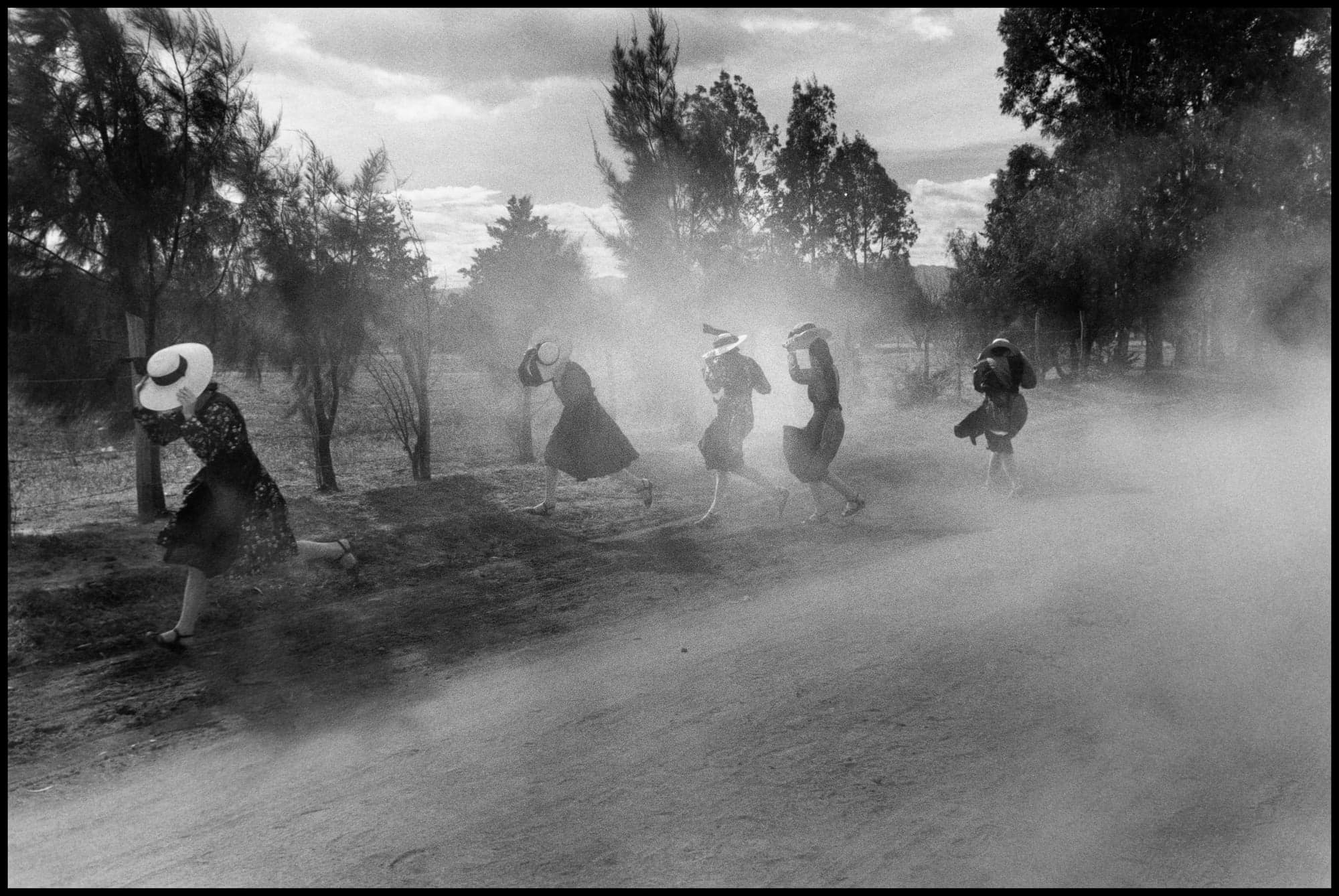 Young Mennonite women fleeing a cloud of dust.