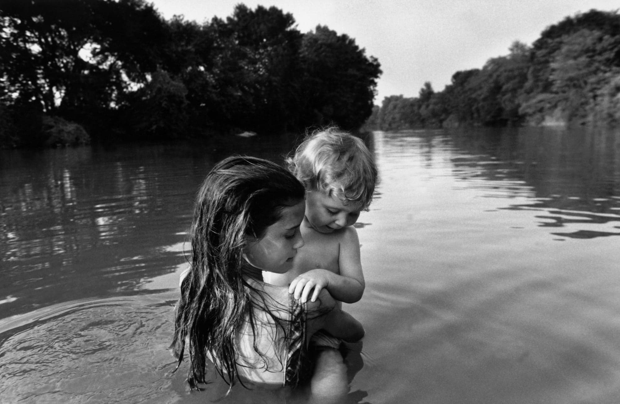 A little girl holding a baby in the river