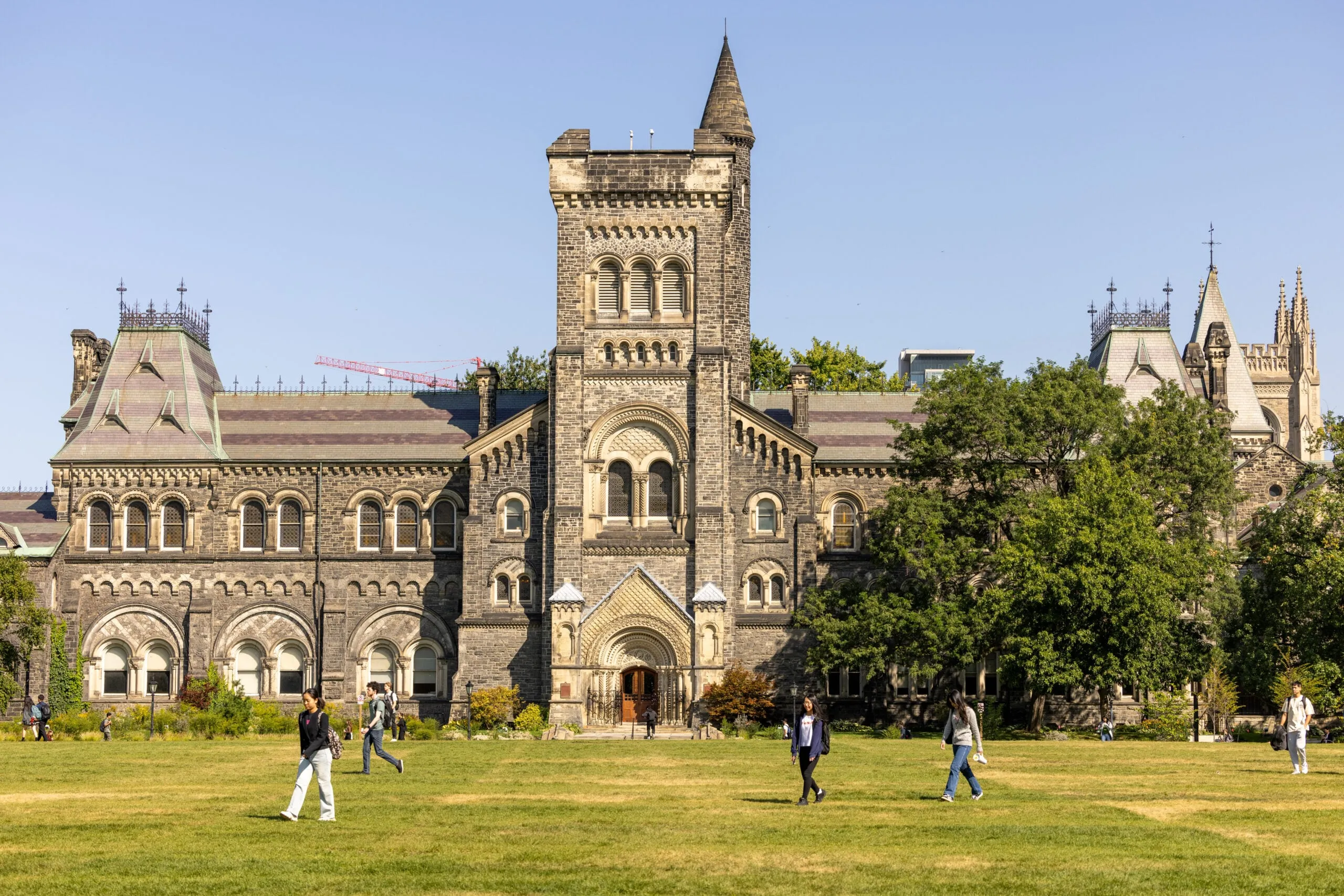 Students throwing a frisbee in front of a university building