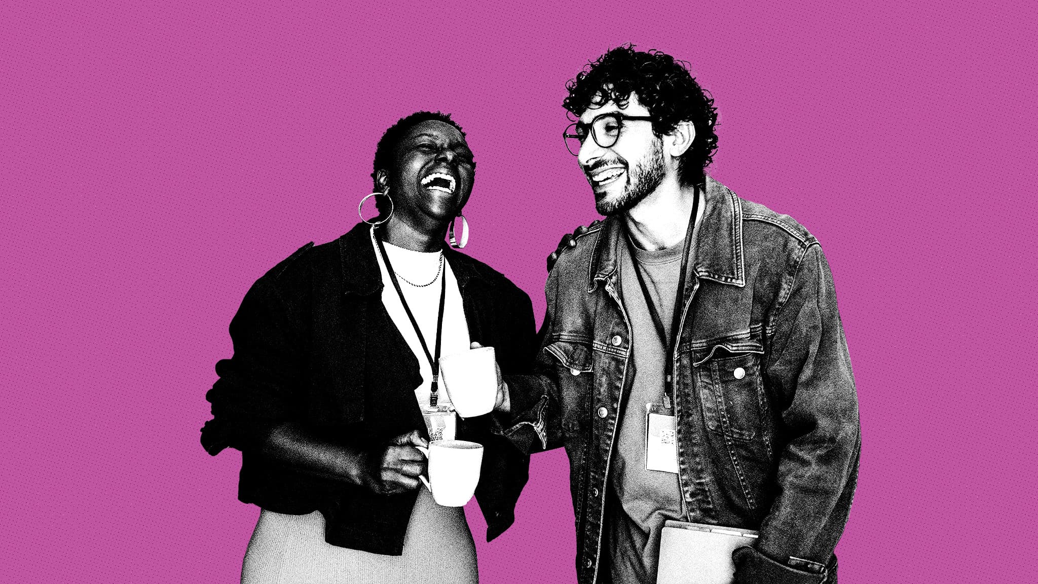 Two colleagues wearing lanyards, holding coffee mugs and laughing together