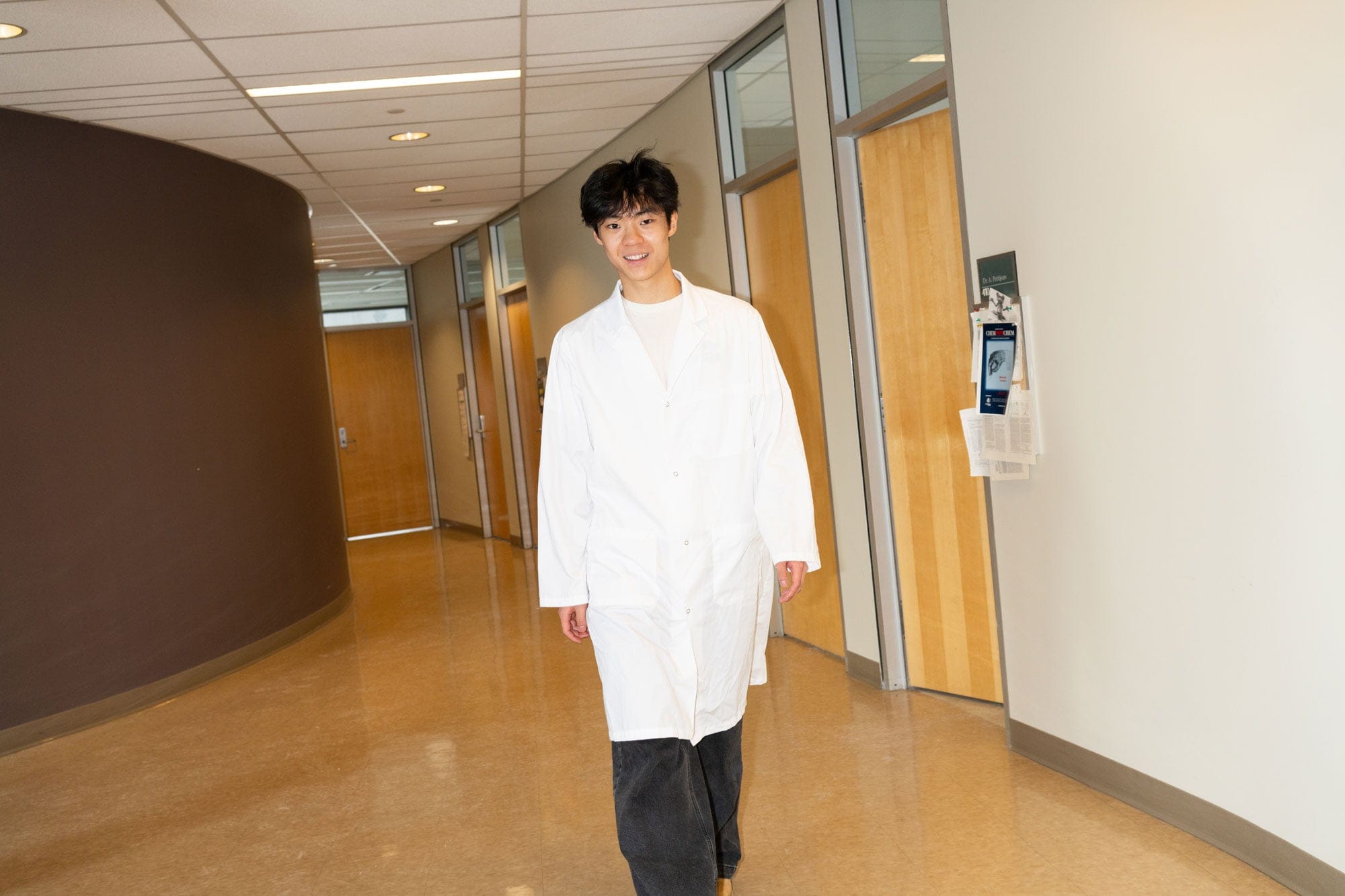 a student in a white coat walking down a hallway