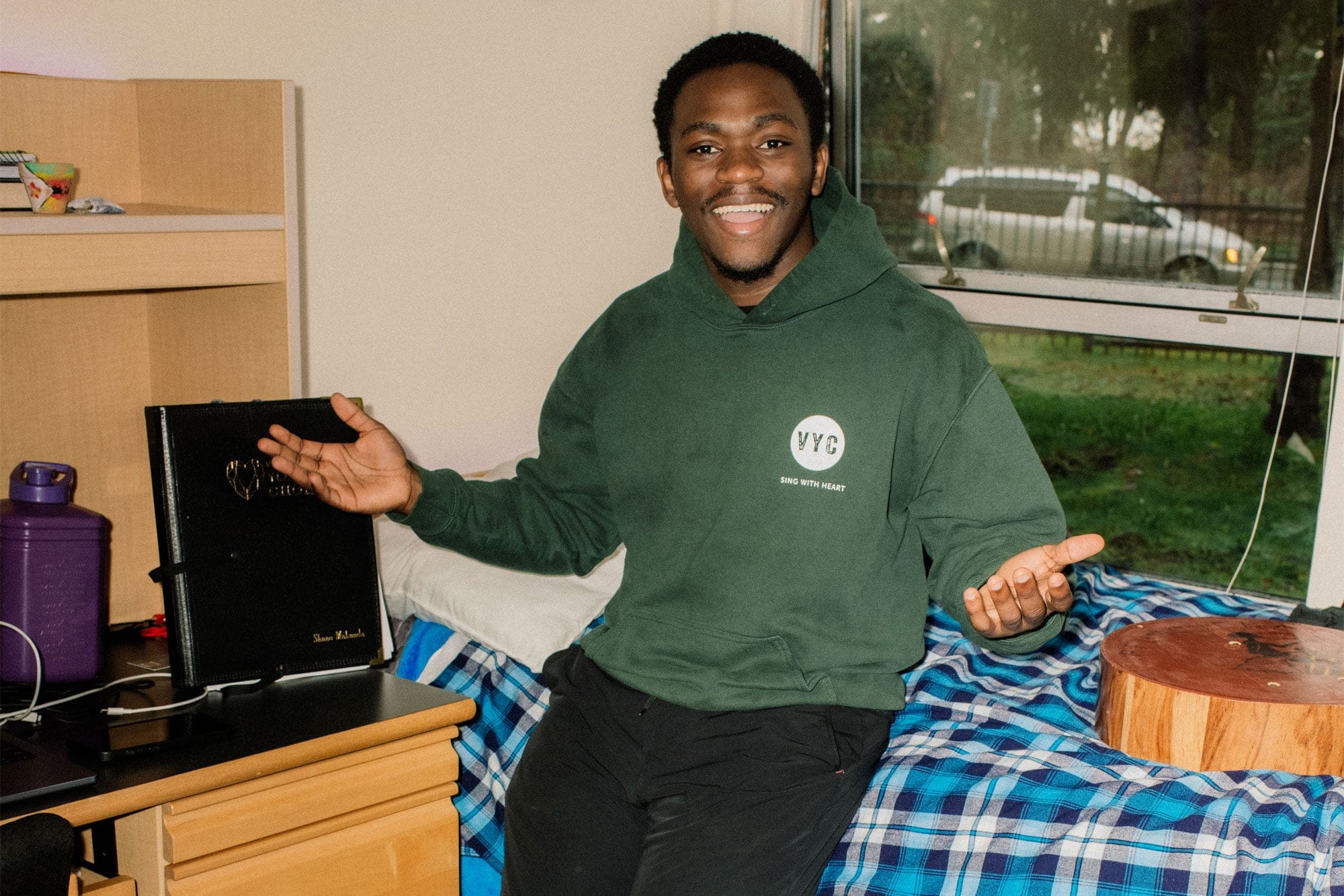 a student sitting on his bed in his dorm room