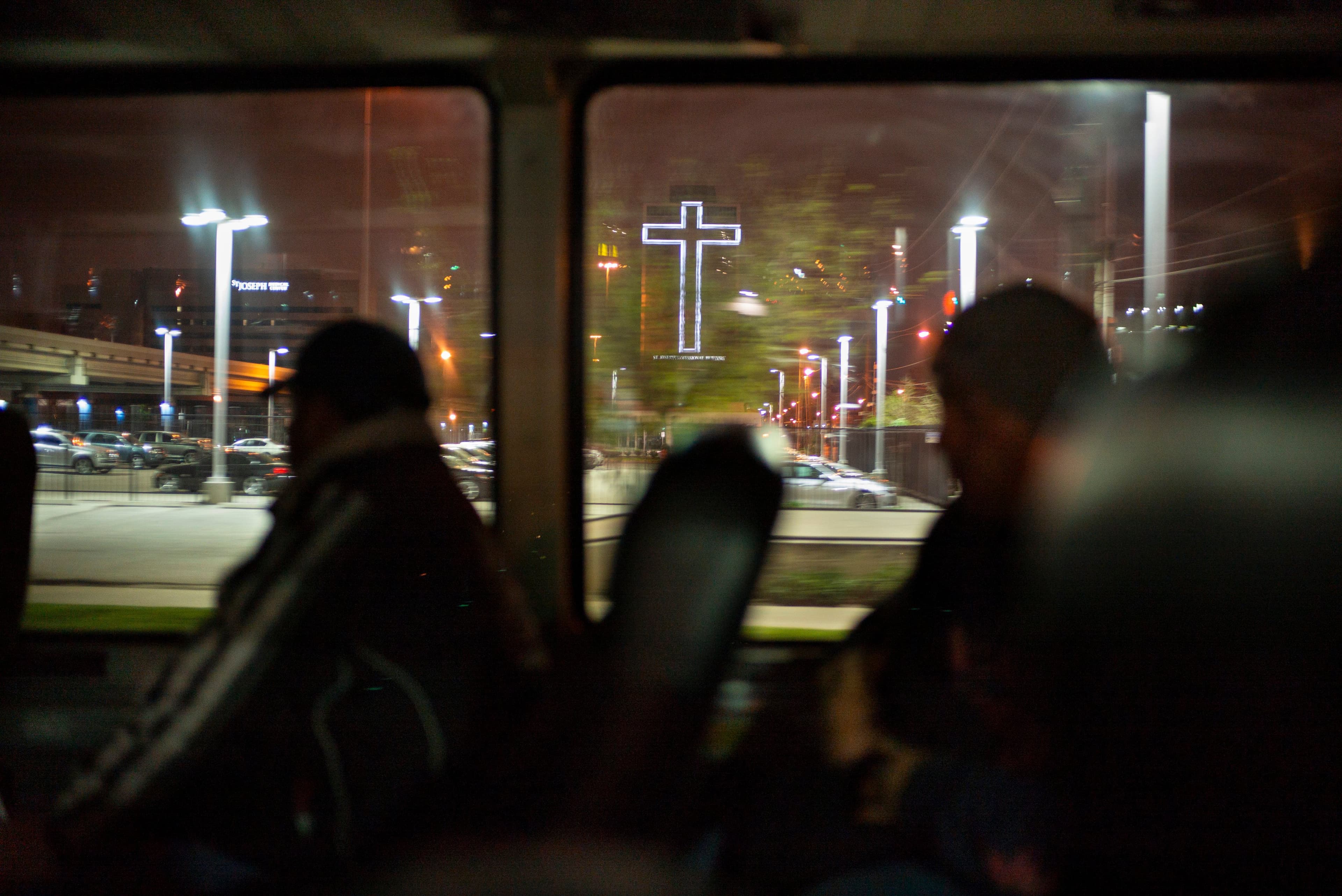 A giant light-up cross as seen from the interior of a bus