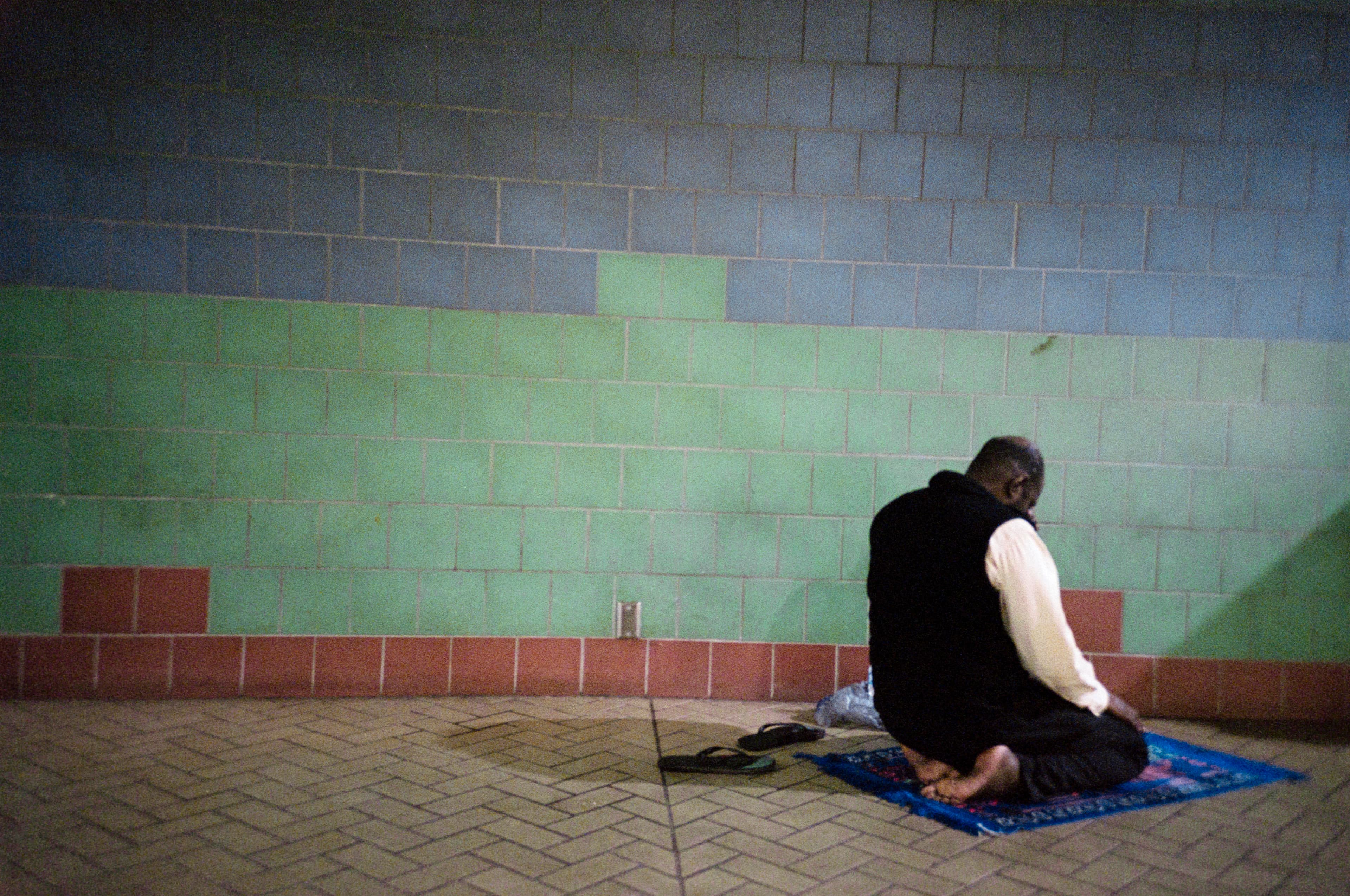 A man praying in front of a wall that looks like a landscape