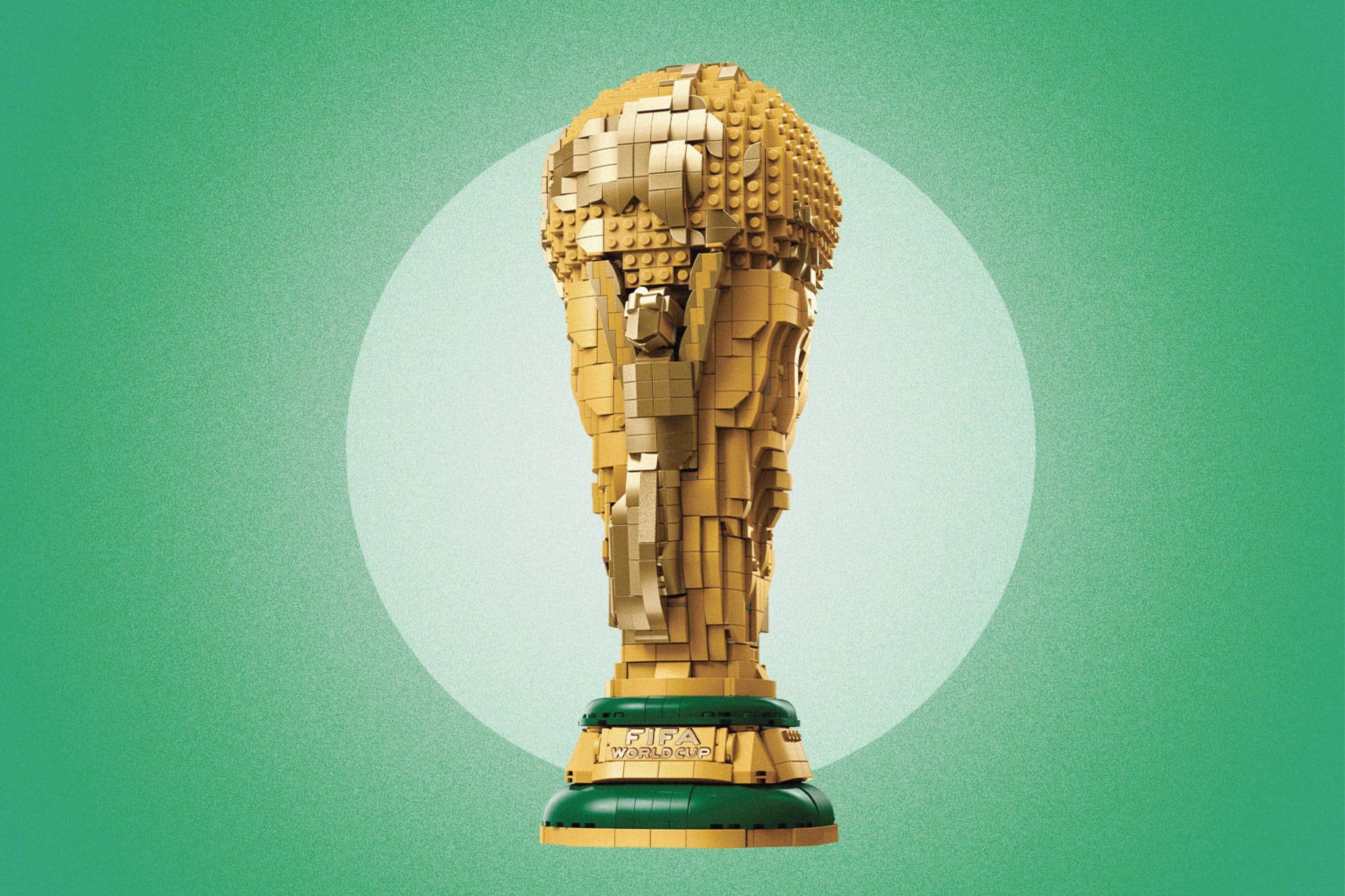 A golden replica of World Cup trophy made of LEGO blocks on the light green coloured background.