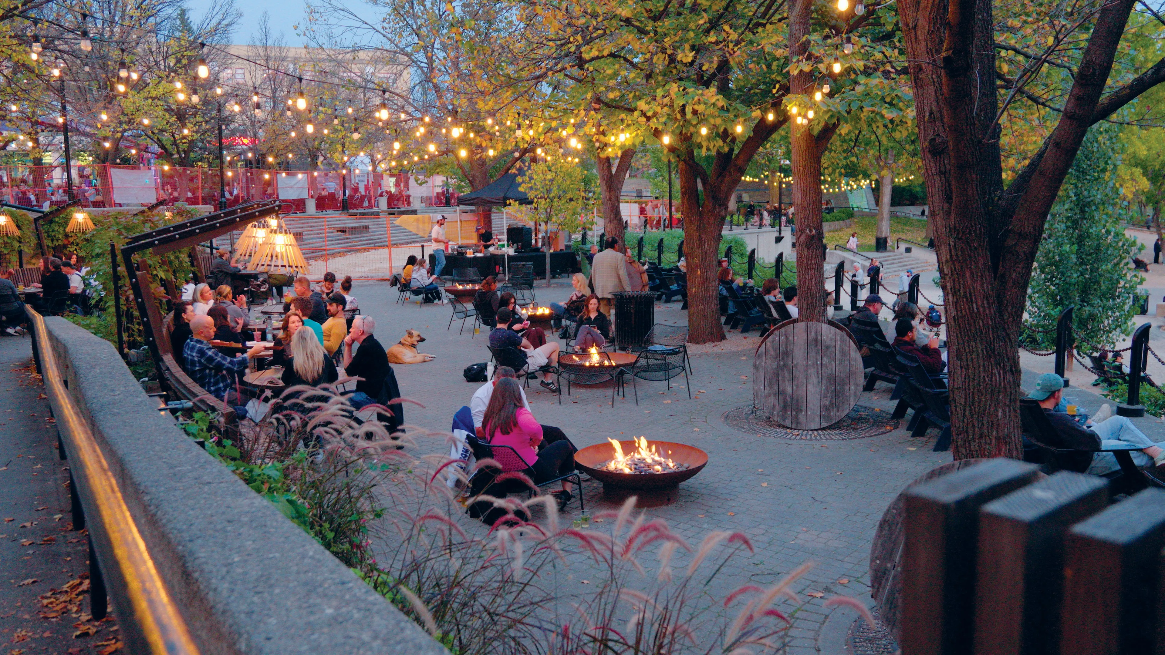 People sitting outside by tables or campfires, talking over foods and beers