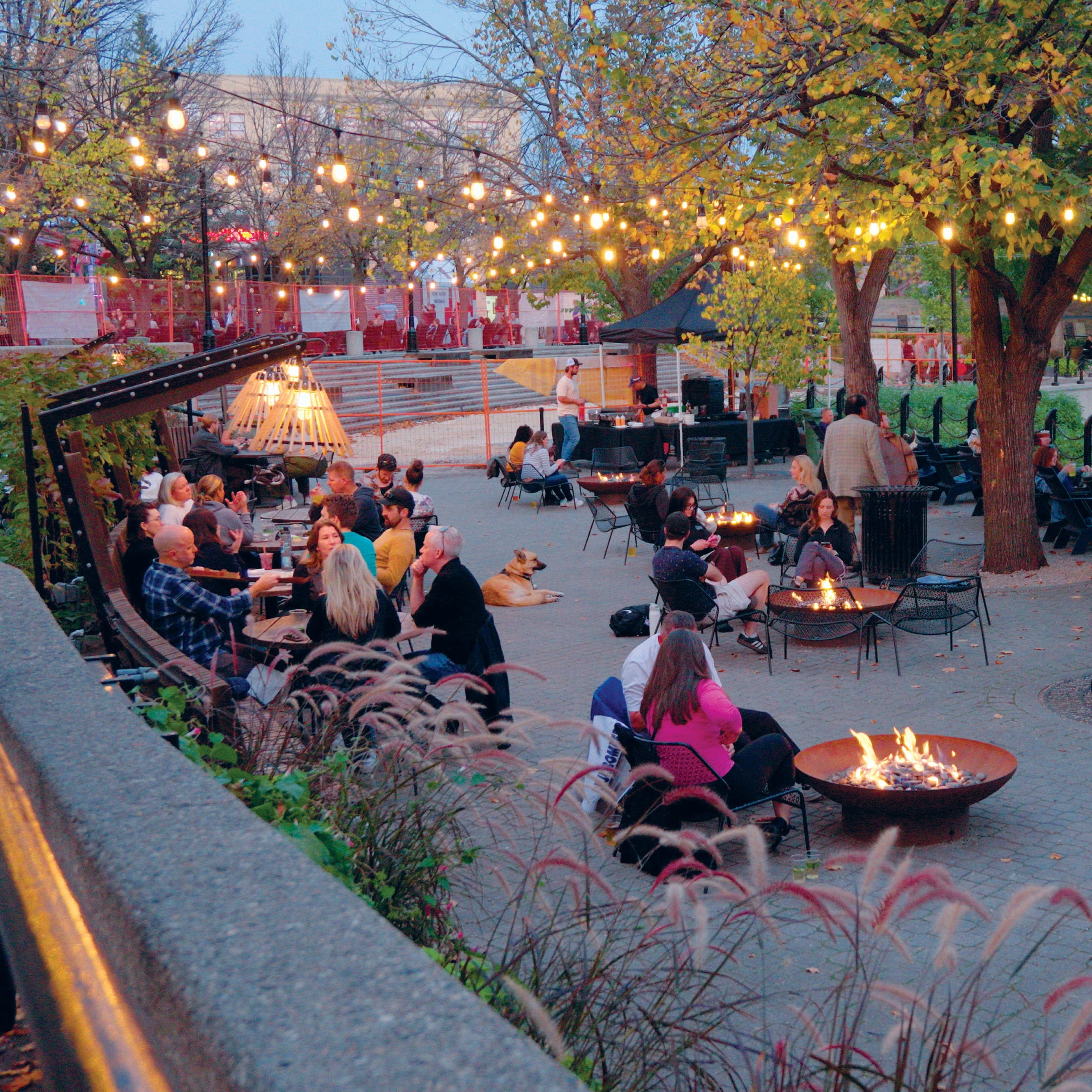 People sitting outside by tables or campfires, talking over foods and beers