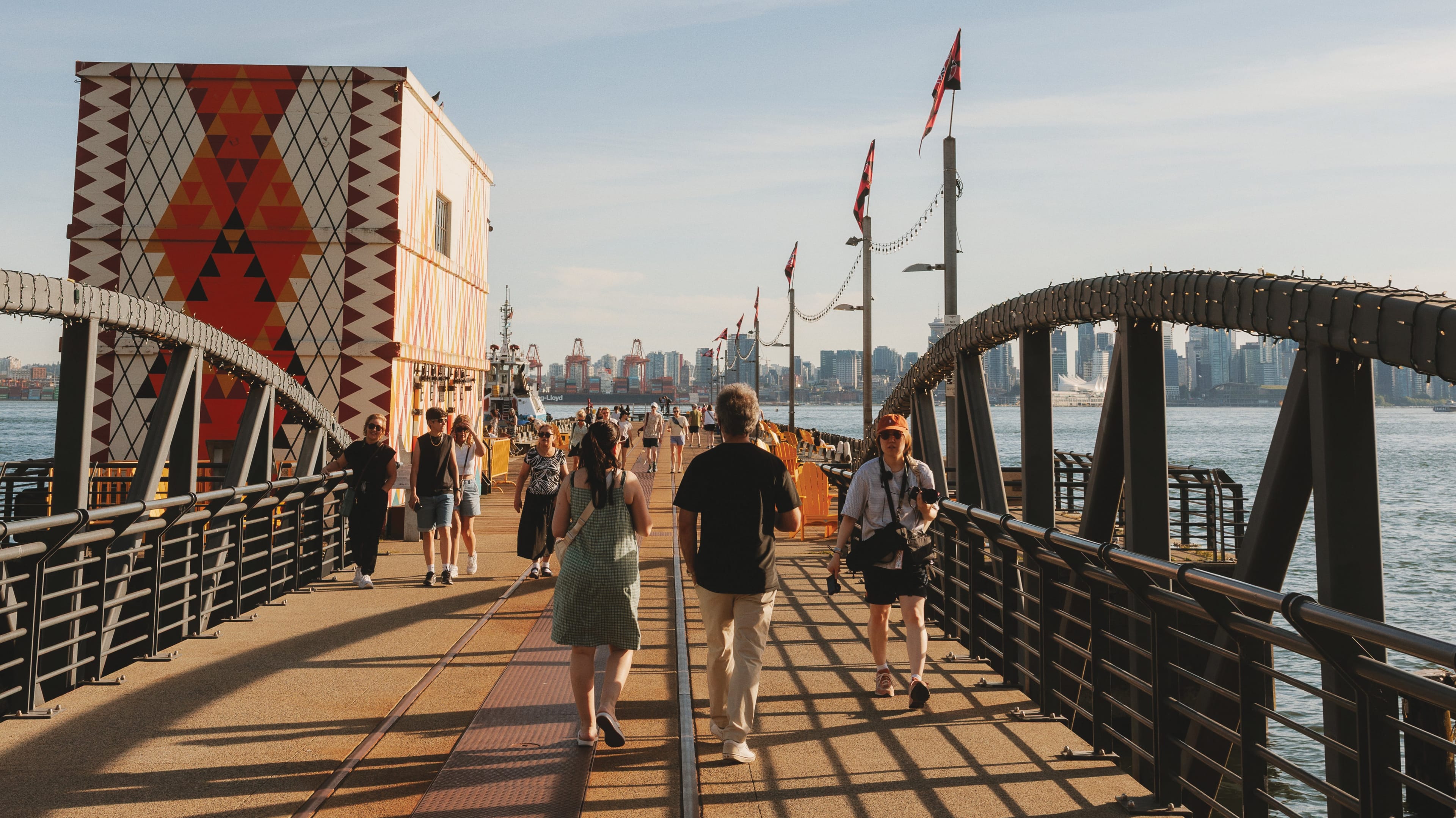 Ocean and a street under the sky and the sunlight, people walking over the bridge