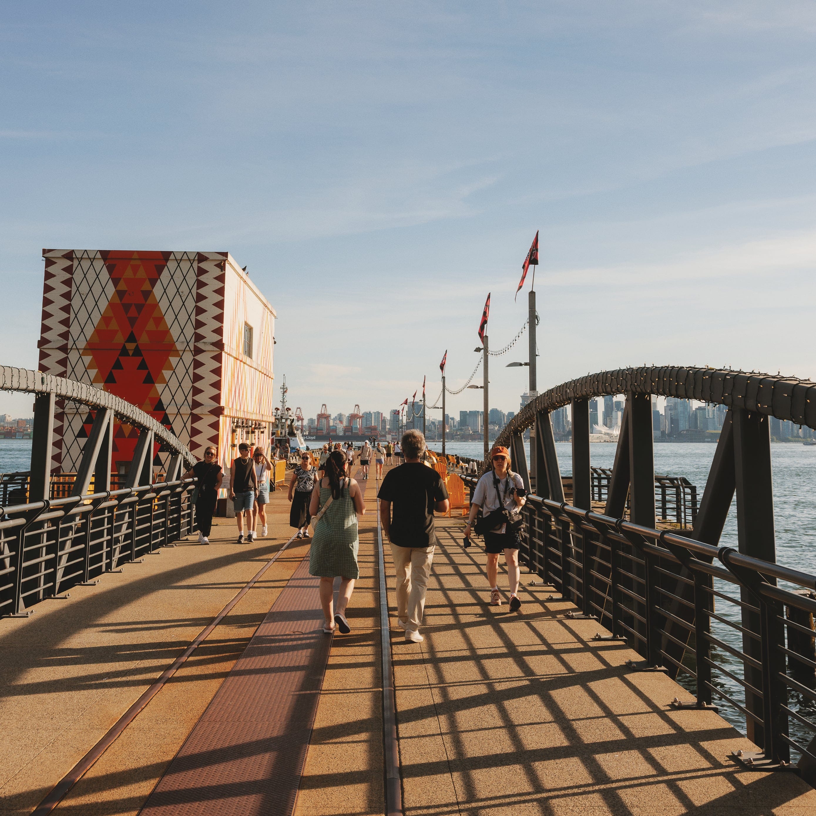 Ocean and a street under the sky and the sunlight, people walking over the bridge
