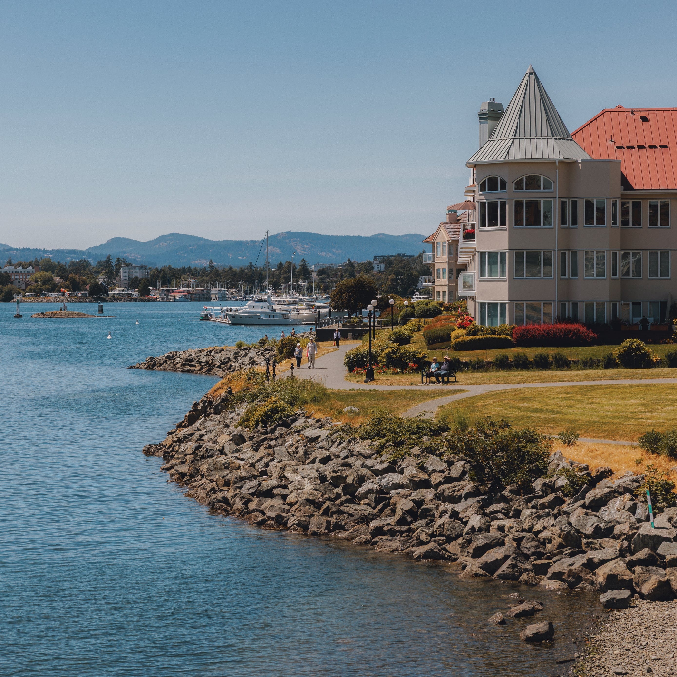 Shore under the blue sky, with the ocean and a building side by side, white boats in the background