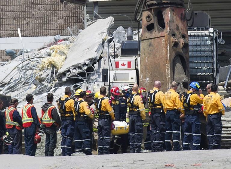<p>Rescue workers remove their hard hats as firefighters carry a second body out of the Algo Centre Mall in Elliot Lake, Ont., on Wednesday, June 27, 2012, after the mall&#8217;s roof collapsed last Saturday. Provincial police in Ontario announce criminal investigation into the fatal mall roof collapse in Elliot Lake. THE CANADIAN PRESS/Nathan Denette</p>
