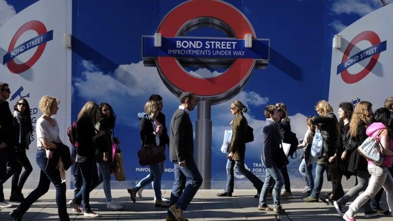 <p>People walk past signs for a London Underground improvement programme during a busy afternoon on Oxford Street in London. </p>
