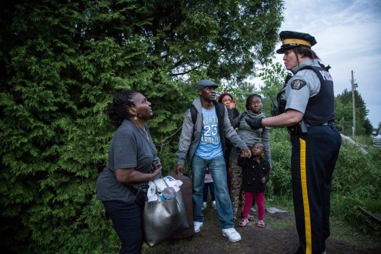 A group of seven people from Nigeria are informed by an RCMP officer of their rights and the law that they are breaking by crossing illegally from the USA into Canada at Roxham Rd. Quebec. (Photograph by Roger LeMoyne)