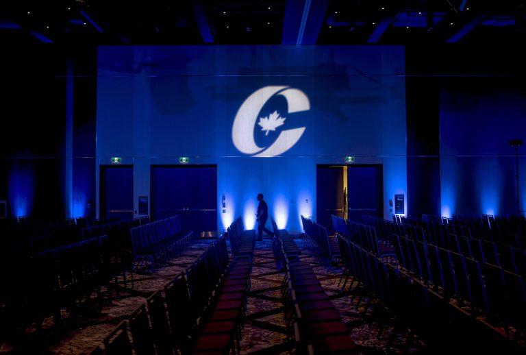A man is silhouetted walking past a Conservative Party logo before the opening of the Party's national convention in Halifax on Thursday, Aug. 23, 2018. (Darren Calabrese/CP)