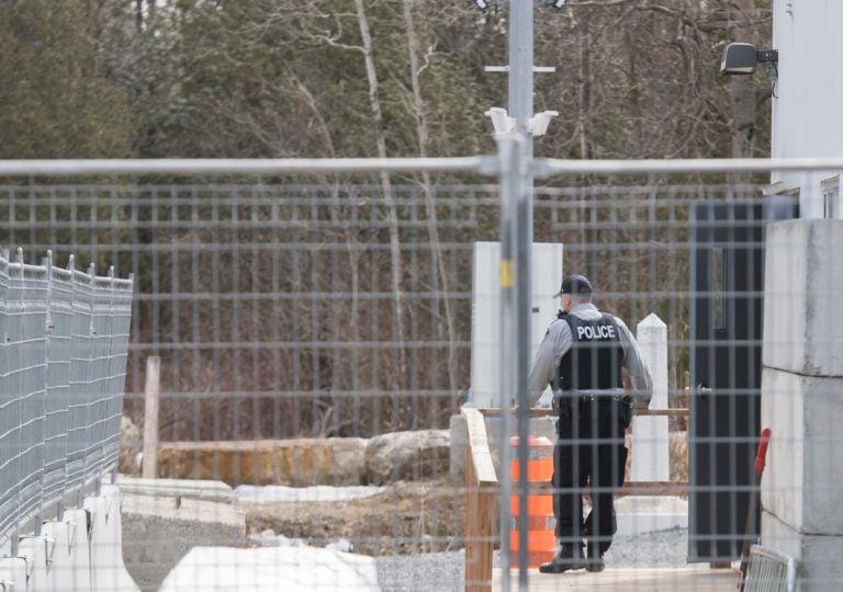 A member of the RCMP looks out towards the United States from an irregular border crossing at Roxham Road, near Hemmingford, Que., on March 19, 2020 (Graham Hughes/THE CANADIAN PRESS IMAGES)