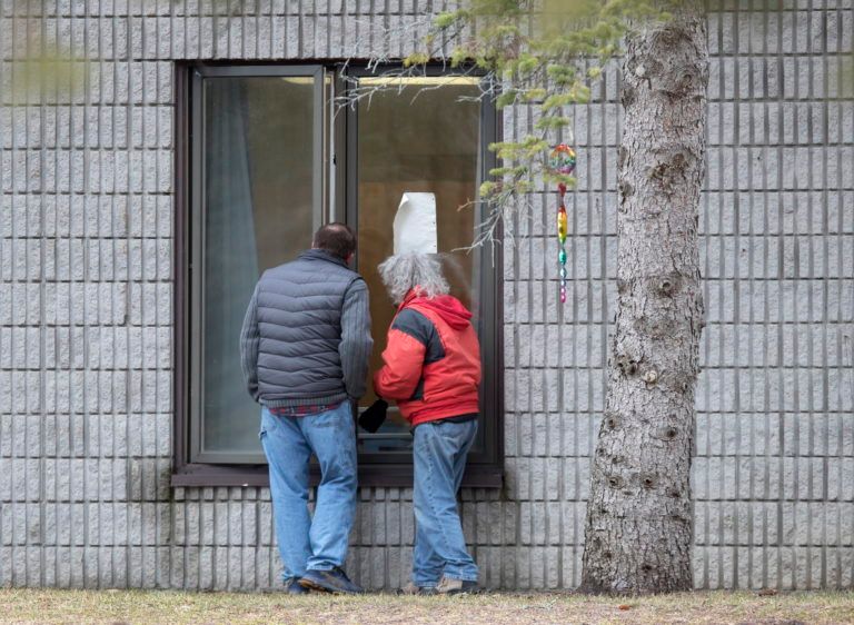 Visitors talk through a window at Pinecrest Nursing Home in Bobcaygeon, Ont., where there has been a deadly COVID-19 outbreak, on March 30, 2020 (CP/Fred Thornhill)