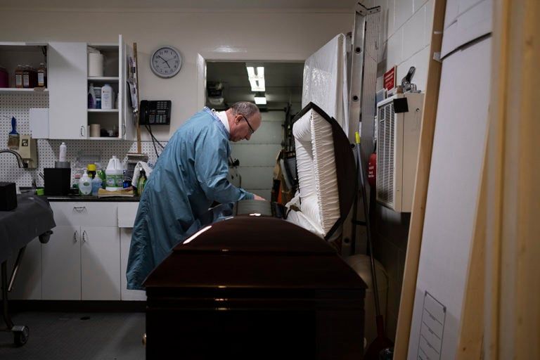 Funeral Director RIchard Paul adjusts a body in a casket. (Photograph by Isaac Paul)