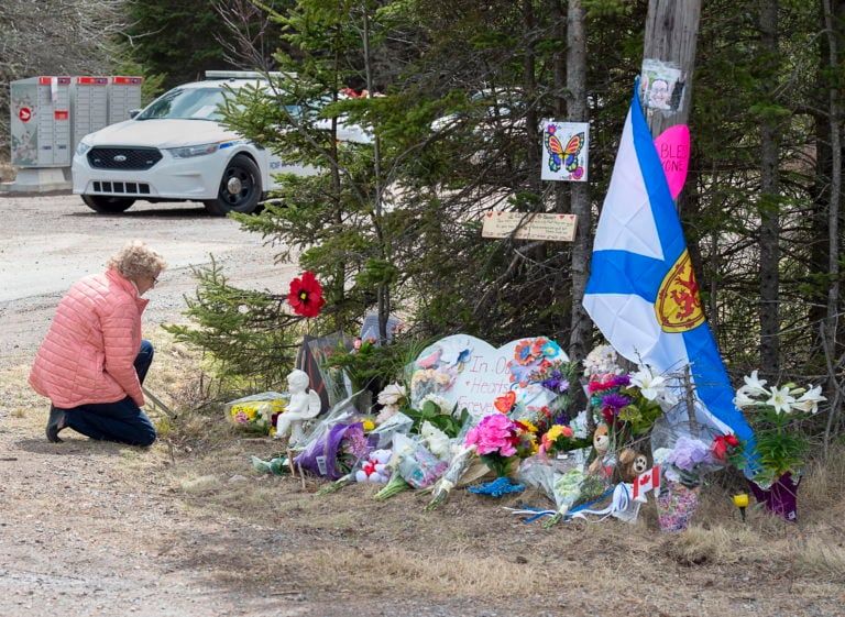 A woman pays repects at a roadside memorial in Portapique, N.S. RCMP revealed that 13 of the 22 people killed last weekend by a man on a shooting and arson spree died in the tiny community. (Andrew Vaughan/CP)
