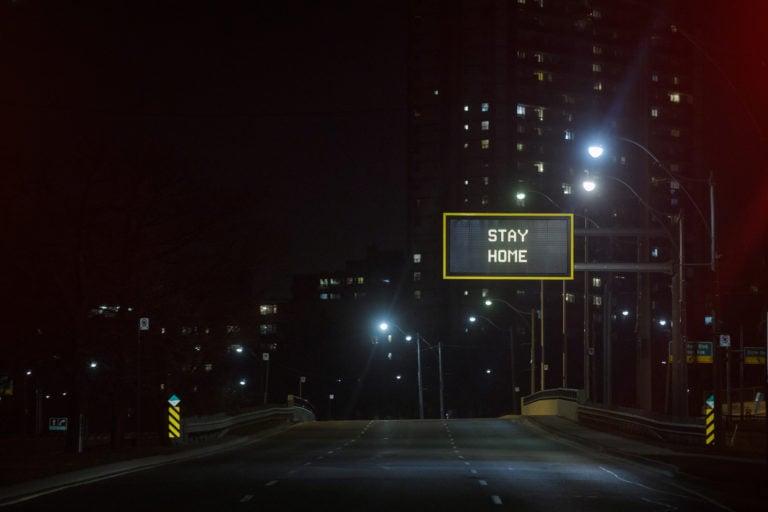 "Stay Home" is displayed on a sign over an empty road in Toronto, on March 25, 2020. (Cole Burston/Bloomberg/Getty Images)