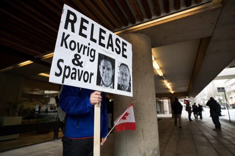 A man holds a sign bearing photographs of Kovrig and Spavor outside B.C. Supreme Court where Meng was attending a hearing in Vancouver on Jan. 21, 2020 (CP/Darryl Dyck)