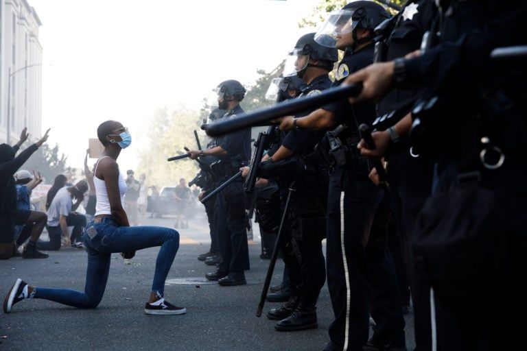 A young woman takes a knee in front of police officers during a protest in San Jose, Calif., on May 29 (Dai Sugano/MediaNews Group/The Mercury News/Getty Images)