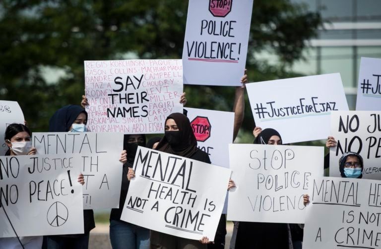 People hold signs in solidarity during a rally for justice for Ejaz Choudry, a 62-year-old man who was recently killed in a Peel Regional Police-involved shooting, in Mississauga, Ont., on Jun. 27, 2020. (Tijana Martin/CP)